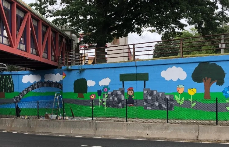 A mural painted by students at Birchwood Intermediate School brightens the LIRR underpass in Huntington Station. The mural has gotten tons of positive feedback from the community, showing the children that what they are doing matters.