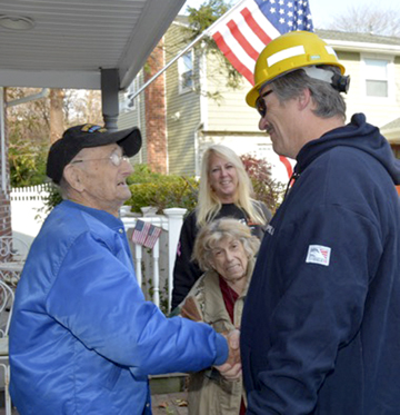 Morris Koffer thanks PSEG Long Island employee Frank Moorhus who organized volunteers to do yard work on the 96-year-old WWII veteran’s property. PSEG photo