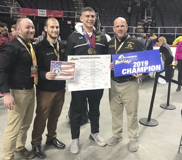 Commack senior Joey Slackman, second from right, celebrates with his coaches after winning the 285-pound state championship on Feb. 23.