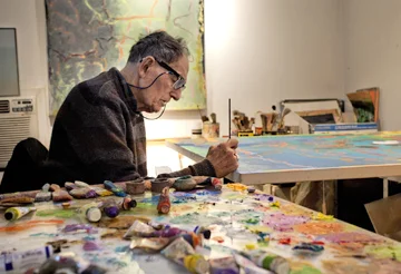 Stan Brodsky signs one of his paintings in his Huntington studio in one of many photographs by Peter Scheer that document the artist and his work. Photo/Peter Scheer