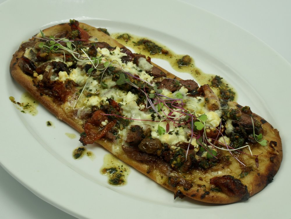  Mediterranean Flatbread with tenderloin, caramelized red onion, kalamata olives, cured tomato, feta, fontina and toasted pistachio pesto. 