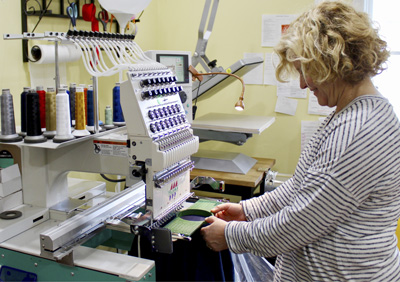 Terri Ehrman places a piece of fabric in the hoop of the embroidery machine at her business, Interthread Embroidery.
