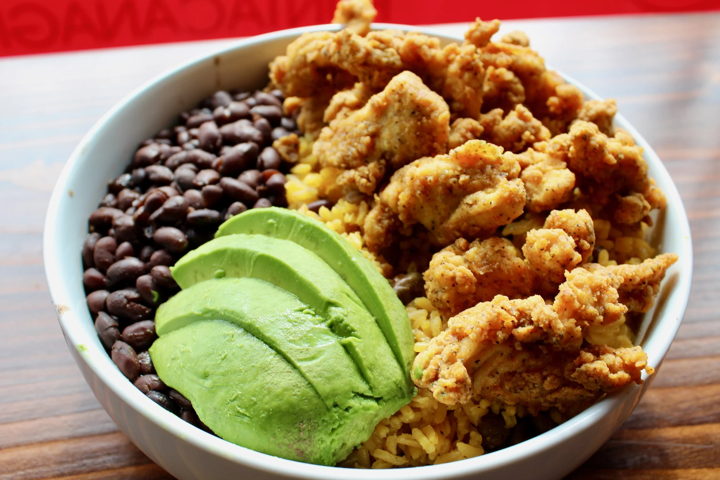  Cana bowl with chicken, yellow rice and peas, black beans, and avocado. 
