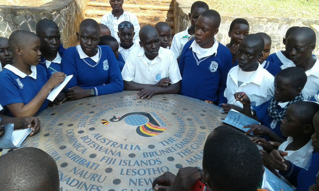 Pupils learning about the countries named on the commonwealth stone near the source of the River Nile.