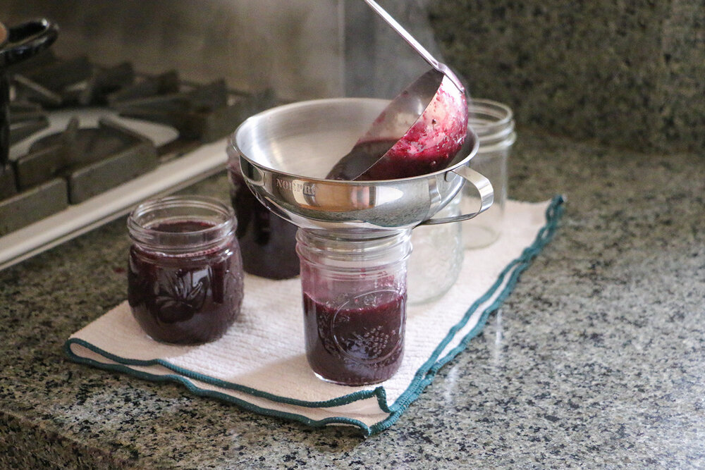 Funnel cooked jelly into mason jars