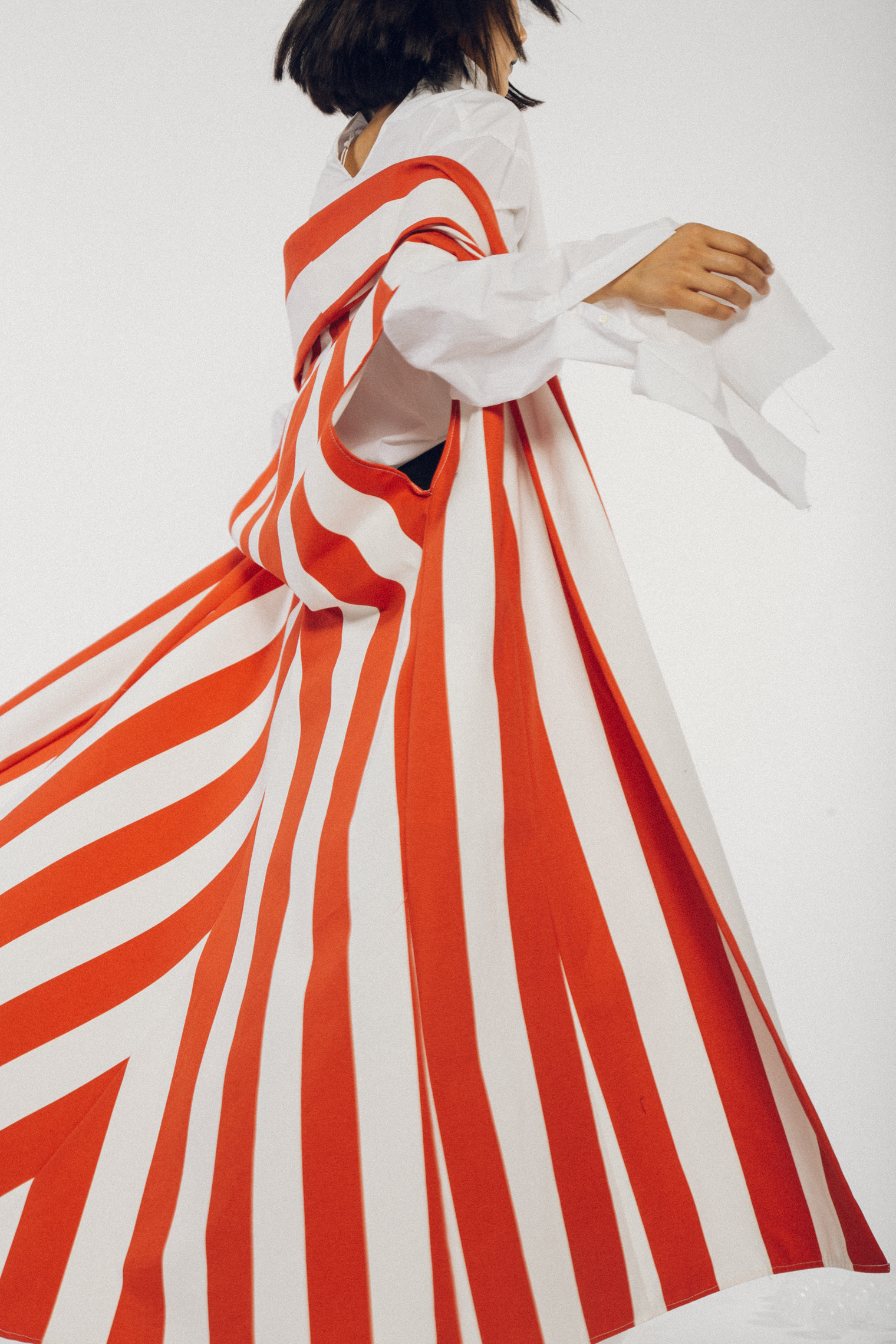 Woman twirls in a bold red and white striped coat