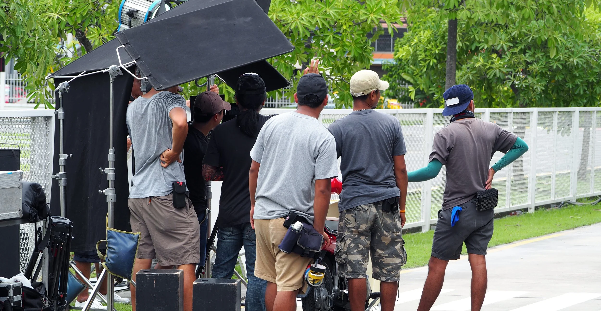 Behind the scenes of vdo production or video shooting at outdoor. Snap shot of film production on location in daytime. Film crew team working.