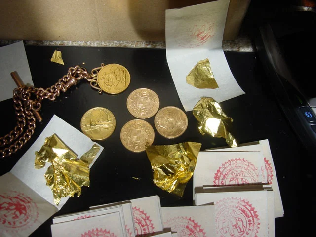 Shown: Gold coins and a pack of 100 gold leaves from Bangkok, Thailand. Each gold leaf is less than a micrometer thick (typically about 100 nm) and is so light and delicate that the smallest puff of air can blow it away.