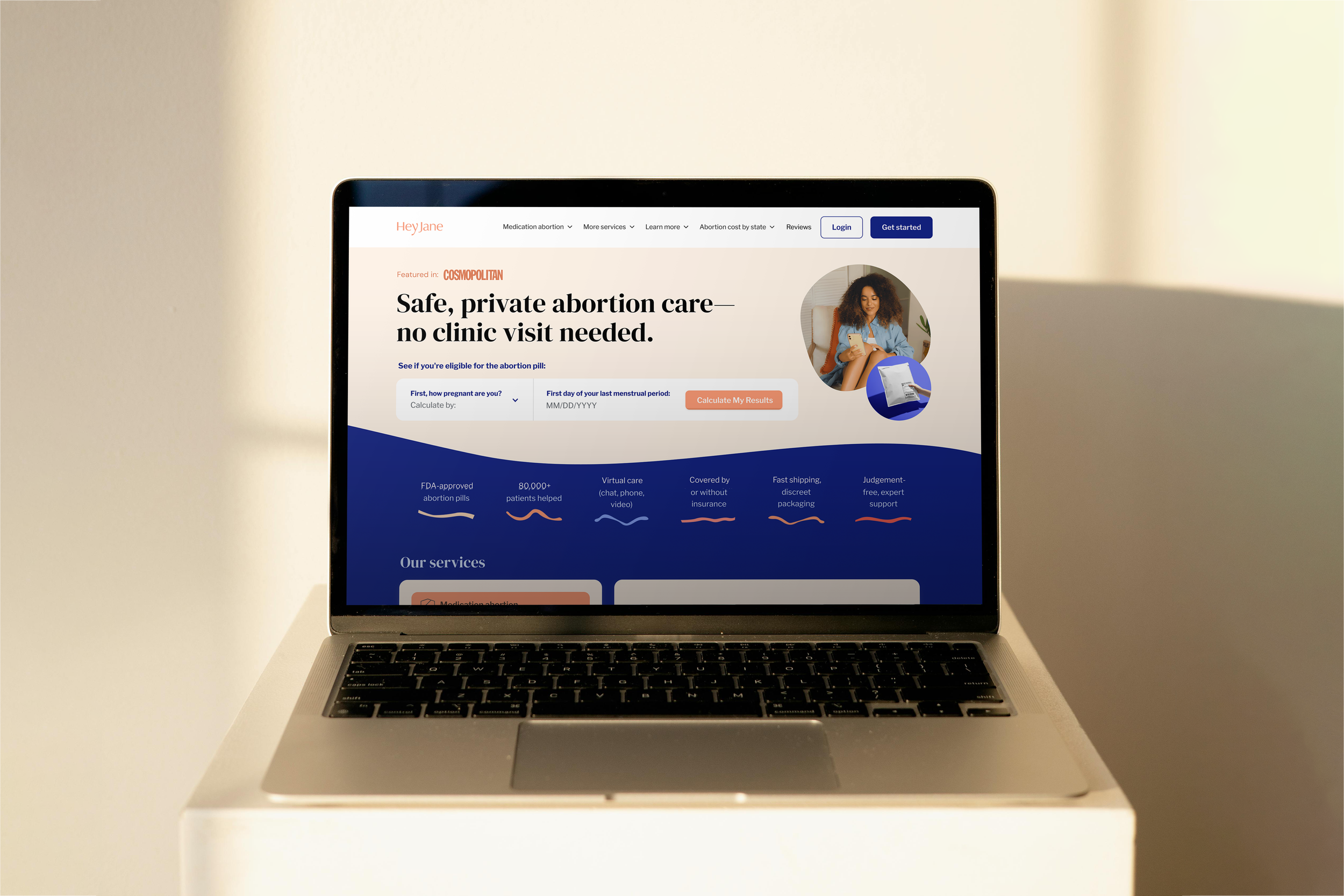 Laptop with a website about private abortion care on the screen, featuring a woman with curly hair and a baby bump, sitting and looking at her phone.