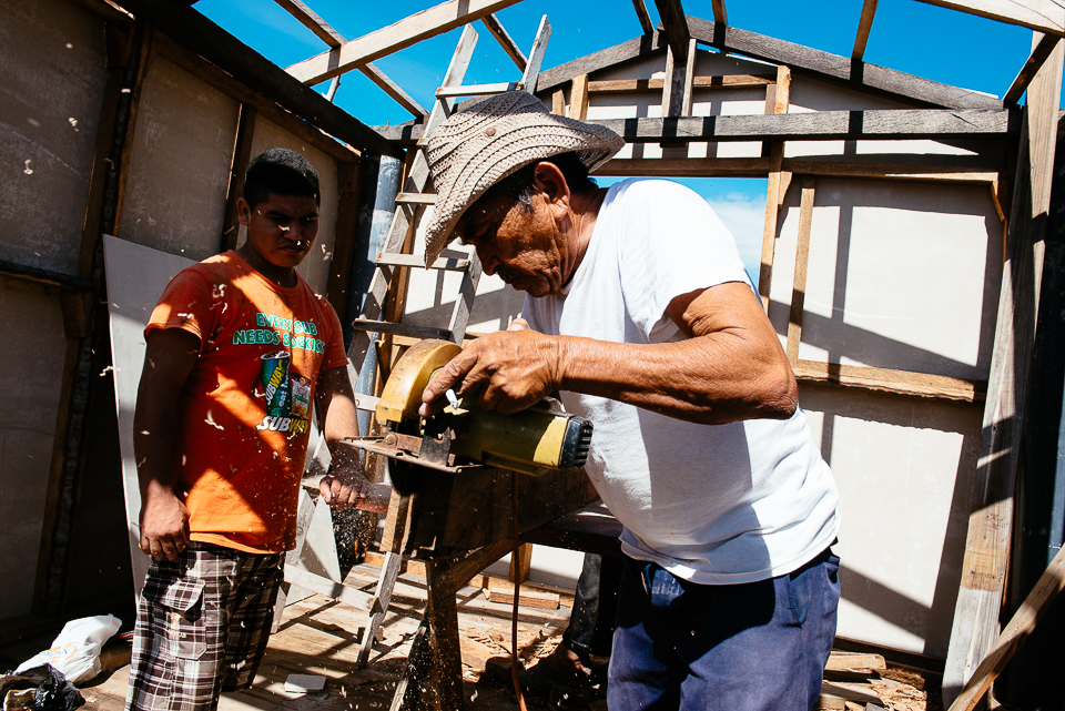 A local Isla la Pirraya man and two friends work on building a new house on pylons over the water. 