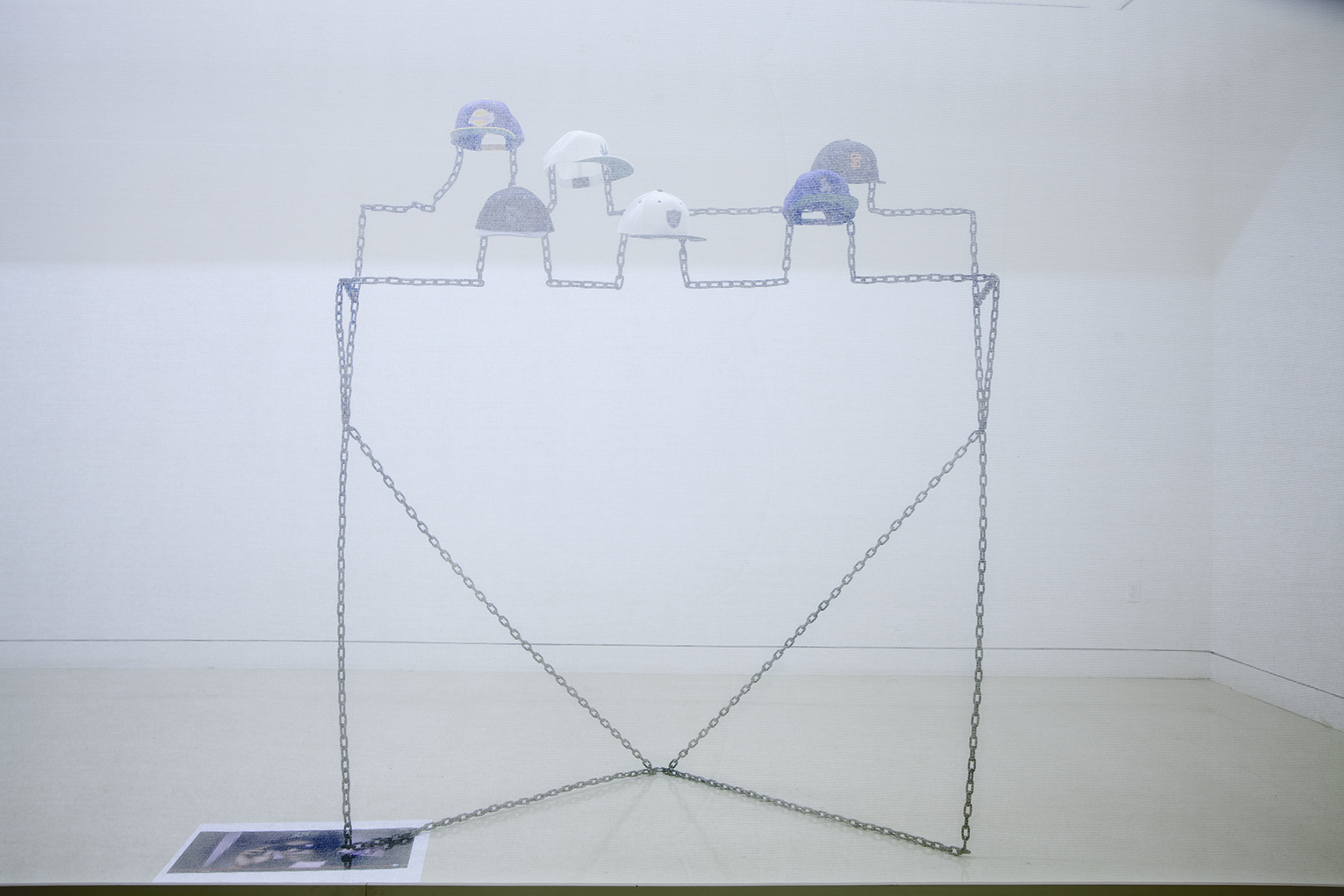  Robin Jiro Margerin  Express yourself (Chain gang)  2014 Six digitally blurred logos embroidered on classic snap-back caps, welded steel chain, color inkjet print Courtesy of the artist 