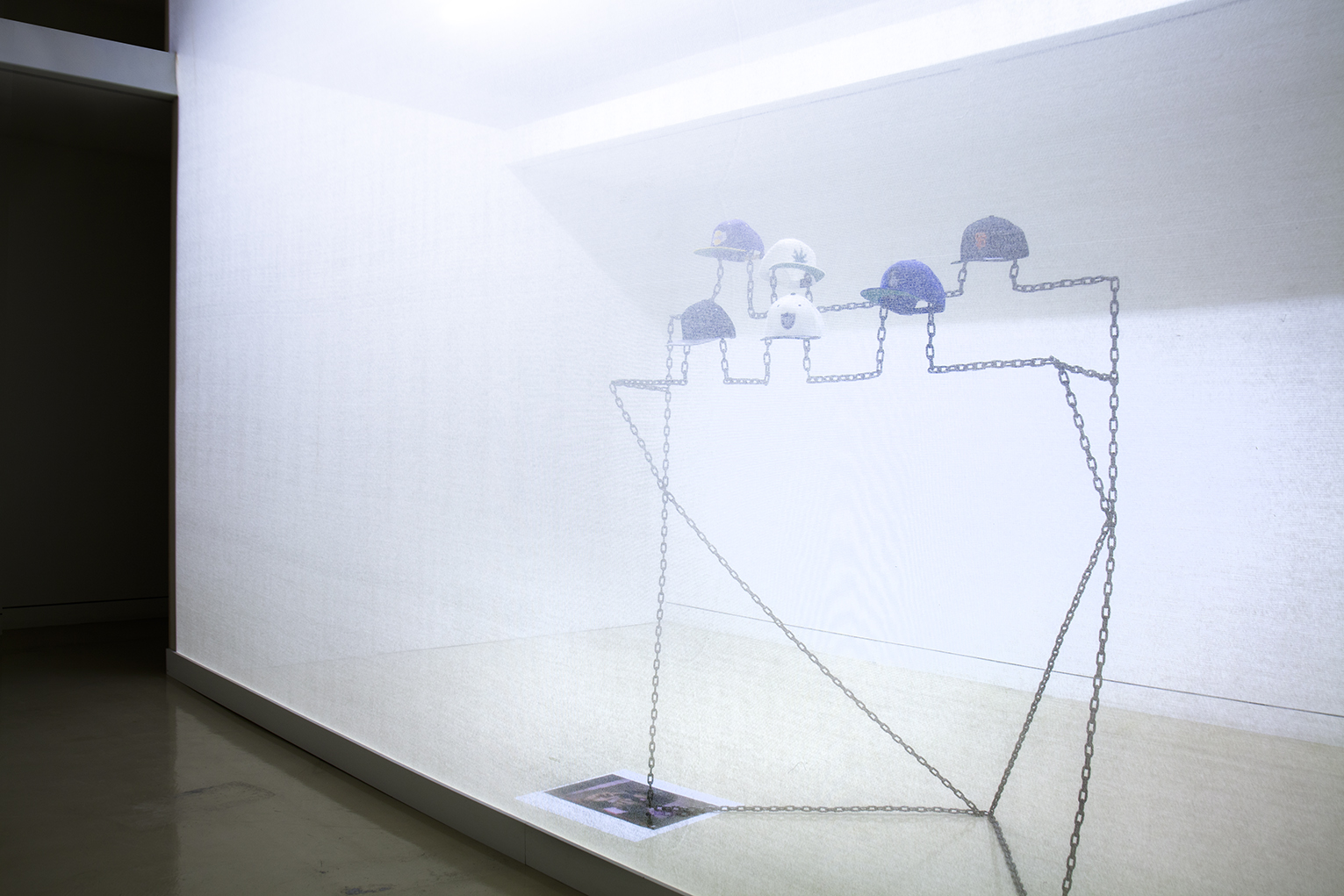 Robin Jiro Margerin Express yourself (Chain gang) 2014 Six digitally blurred logos embroidered on classic snap-back caps, welded steel chain, color inkjet print Courtesy of the artist