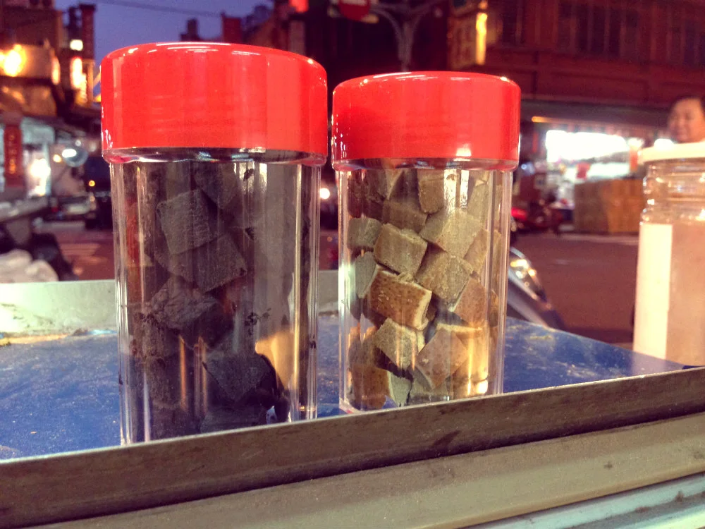 The cough remedy, 八仙果 (which can be translated as "Eight Immortals Fruit"), gets its name from the collection of eight traditional ingredients that are typically used to make it. Before it is diced into cubes like these, its round shape appears a bit grapefruit-like -- which makes, sense, since grapefruit is the standard vessel for all that medicinal goodness. The pale cubes come from grapefruit that has not been peeled, while the darker cubes come from fruit that was peeled before preparation.