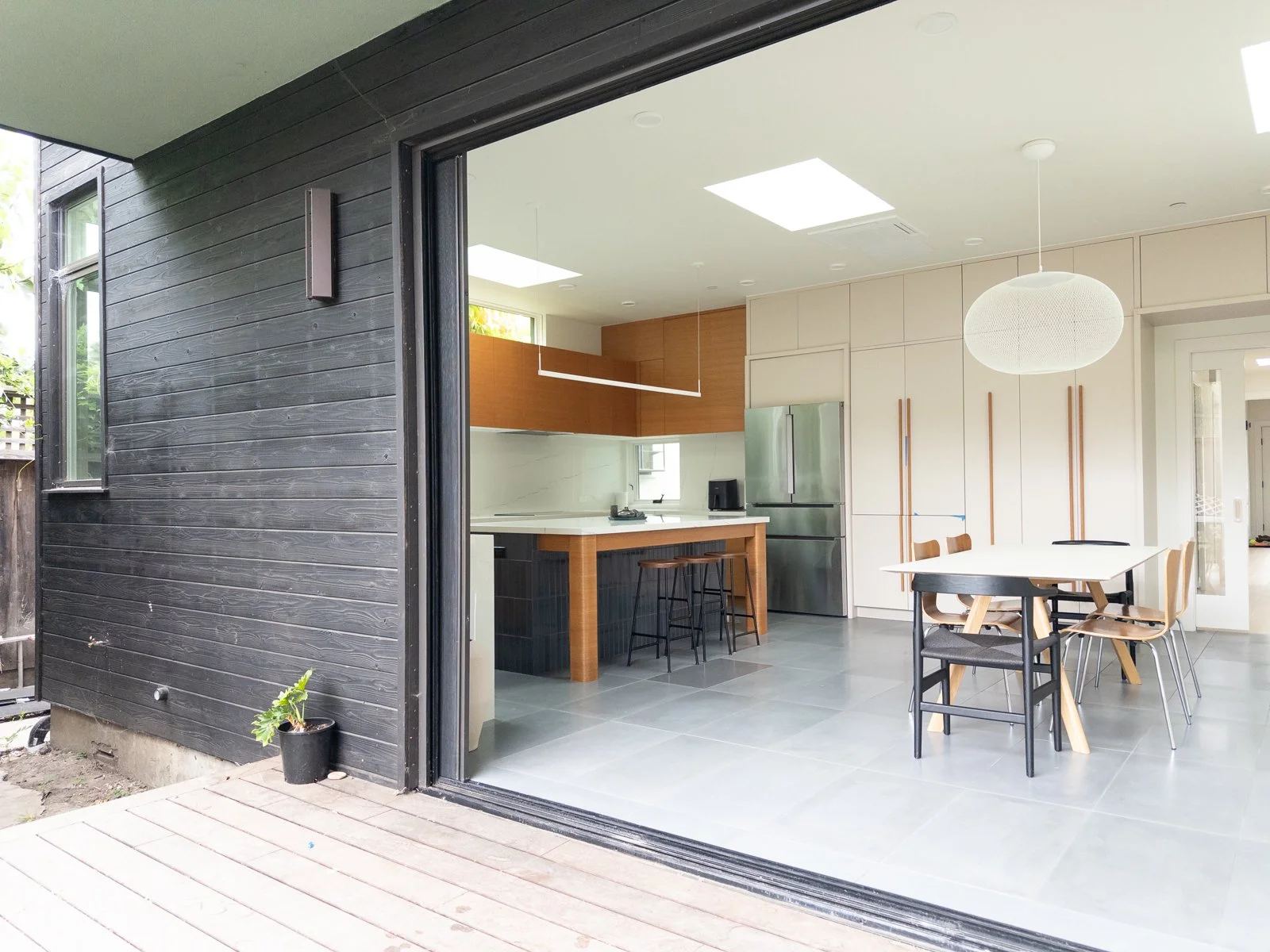  Bi-fold door open to patio and backyard to create indoor / outdoor connection. Addition at rear of house with distinct stained wood siding and cantilevered overhang 