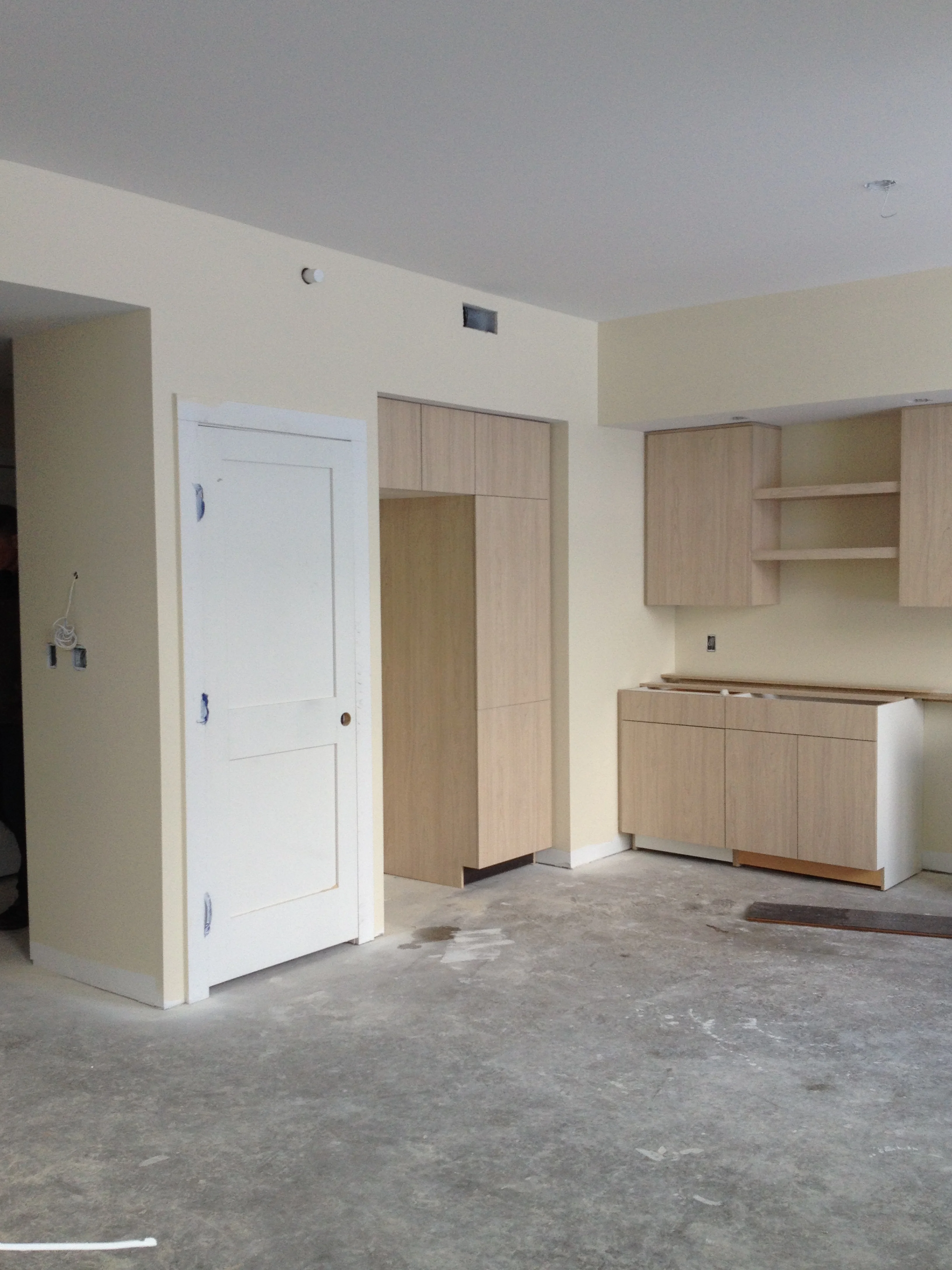 Kitchen cabinets, Refrigerator nook, and pantry in Unit 102.