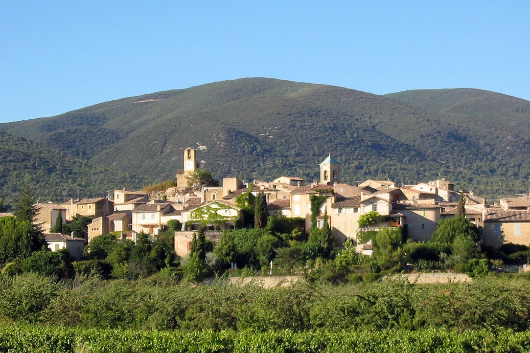 Lourmarin as seen across vineyards and orchardswith the Luberon hills as a backdrop