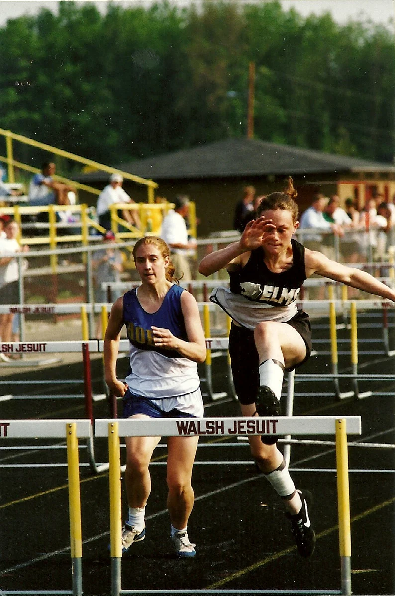 Mary Laske Bell (right) competes in the hurdles at a meet during her high school track career.