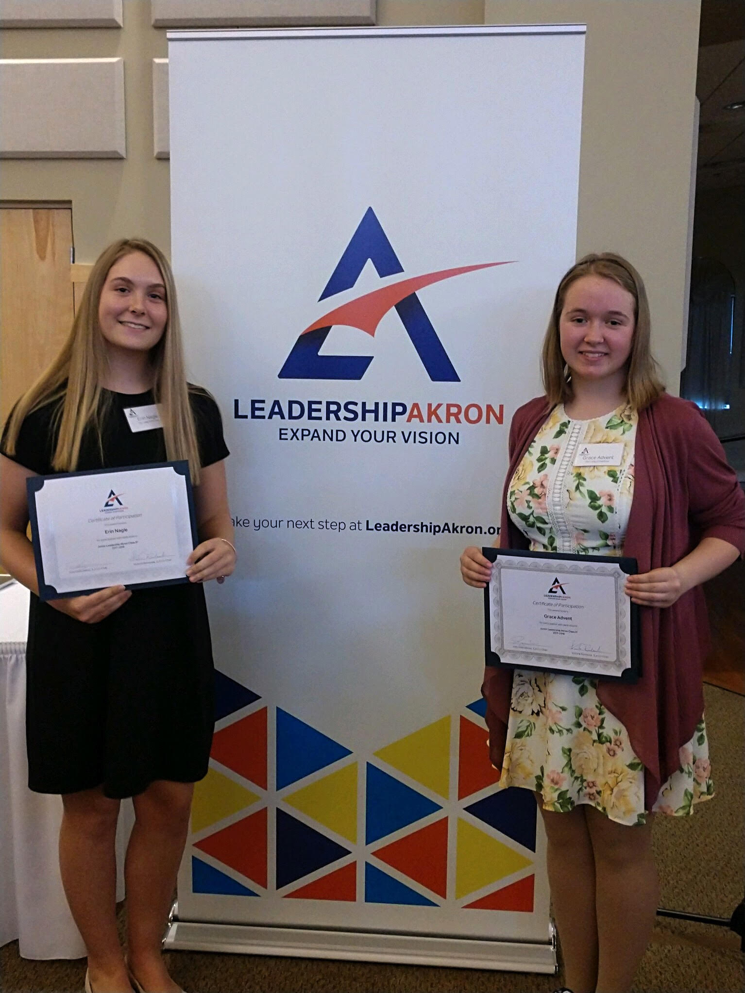 Erin Nagle and Grace Advent display their diplomas from the Leadership Akron graduation ceremony.
