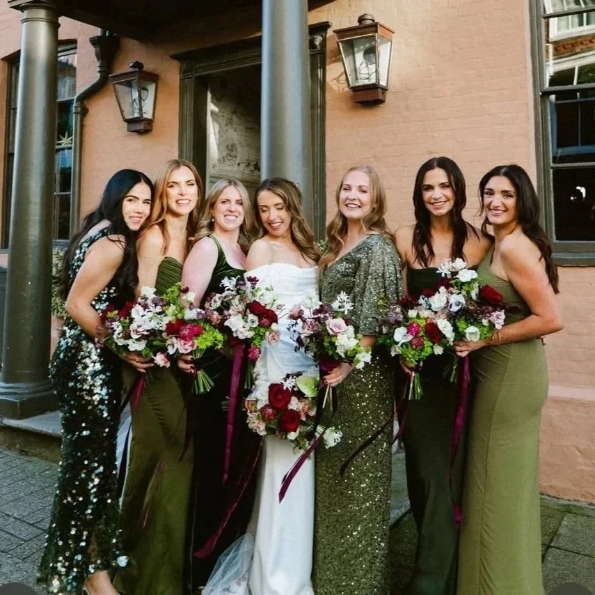 This photo shows a bride and her 6 bridesmaids, lined up outside the George Hotel in Rye, with their stunning burgundy, chartreuse green and white bouquets.