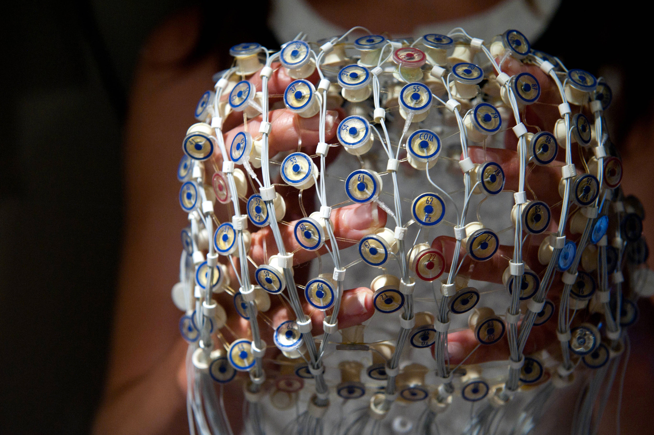 A researcher in the Labs of Cognitive Neuroscience holds a cap used to collect electrical activity from the brain.