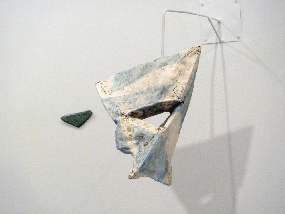 Szilassi Polyhedron , 2011, Clay, glaze and graphite, 15 x 12 x 15 in. When viewed from a specific distance and angle from the piece, the hole in the sculpture is aligned with the shape on the wall. When standing in this “sweet spot”, the viewer can then face towards Heptahedron Set (Transparency, Up and Down) and the markings on the piece simultaneously line up to show the hidden dimensions (the back corner) of the works. These vantage points are intended to create a tension between personal “dogma” and point of view in relation to the General Principal of Relativity which states that all positions and points of reference are equivalent under the laws of physics. 