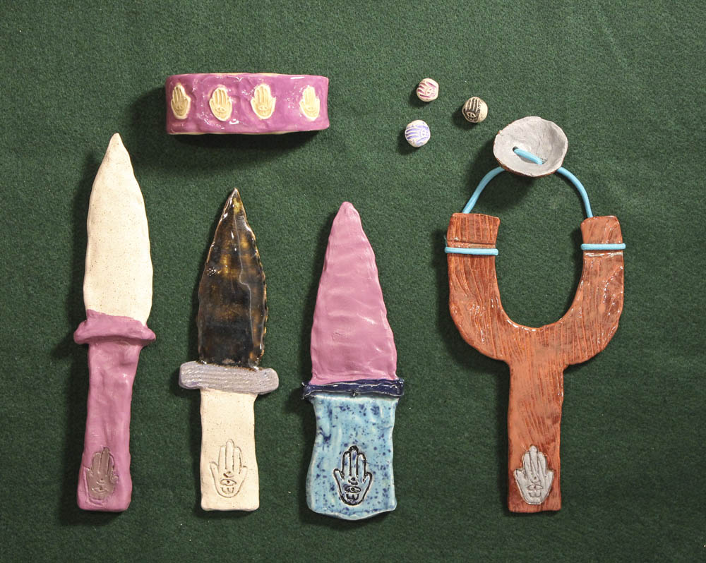  Guy Ben-Ari &amp; Leah Wolff,  The Best Defense is a Good Hamsa , 2012, Clay and glaze   Ben-Ari and Wolff present The Best Defense is a Good Hamsa, which features ceramic hamsa-decorated objects as tools of passive and active offense. The hamsa is 