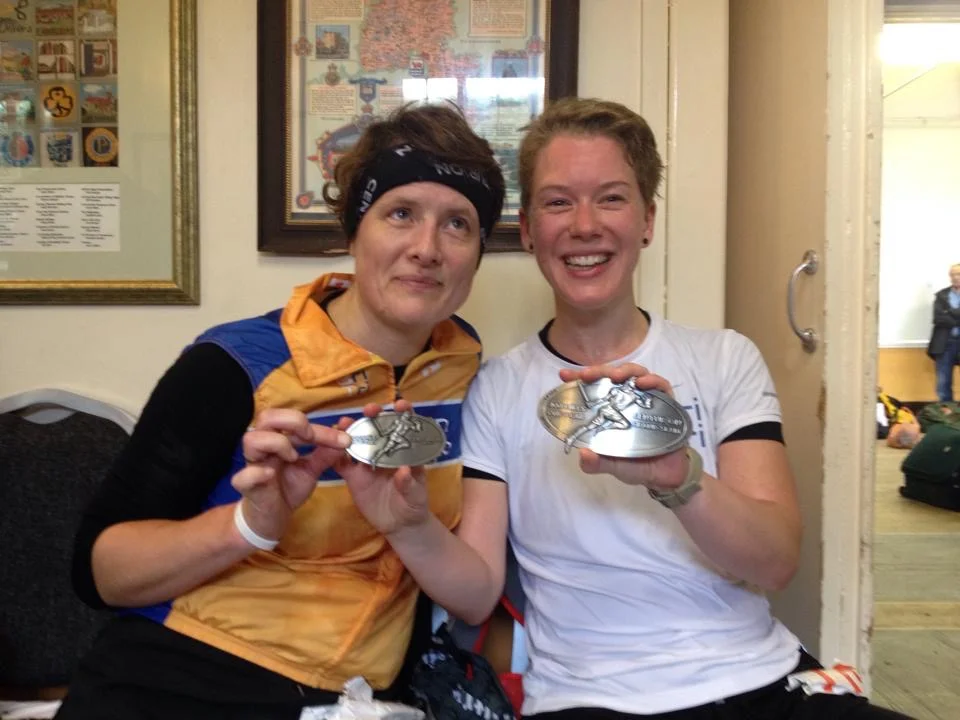 Kat (right), her Grand Slam title and Winter 100 finishers' medals, a smile to make the moon blush, with super supportive pacer Rachel.