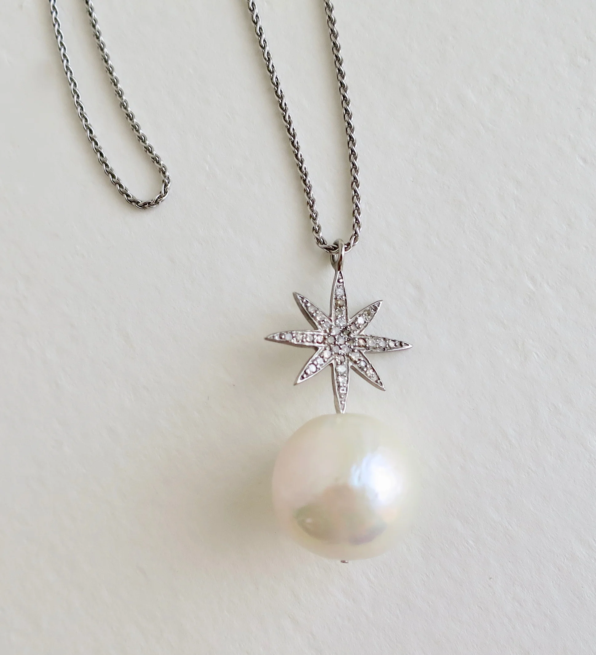 Large drop pearl with silver star set with diamonds 