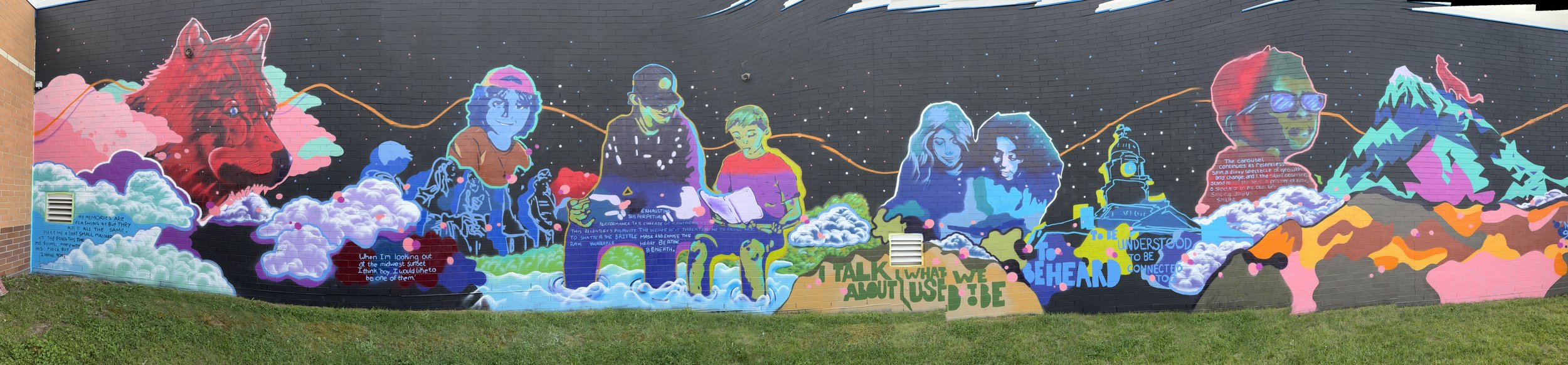 Colorful mural depicting a wolf, people, mountains, clouds, and abstract elements with text and imagery representing mindfulness, connection, and nature.