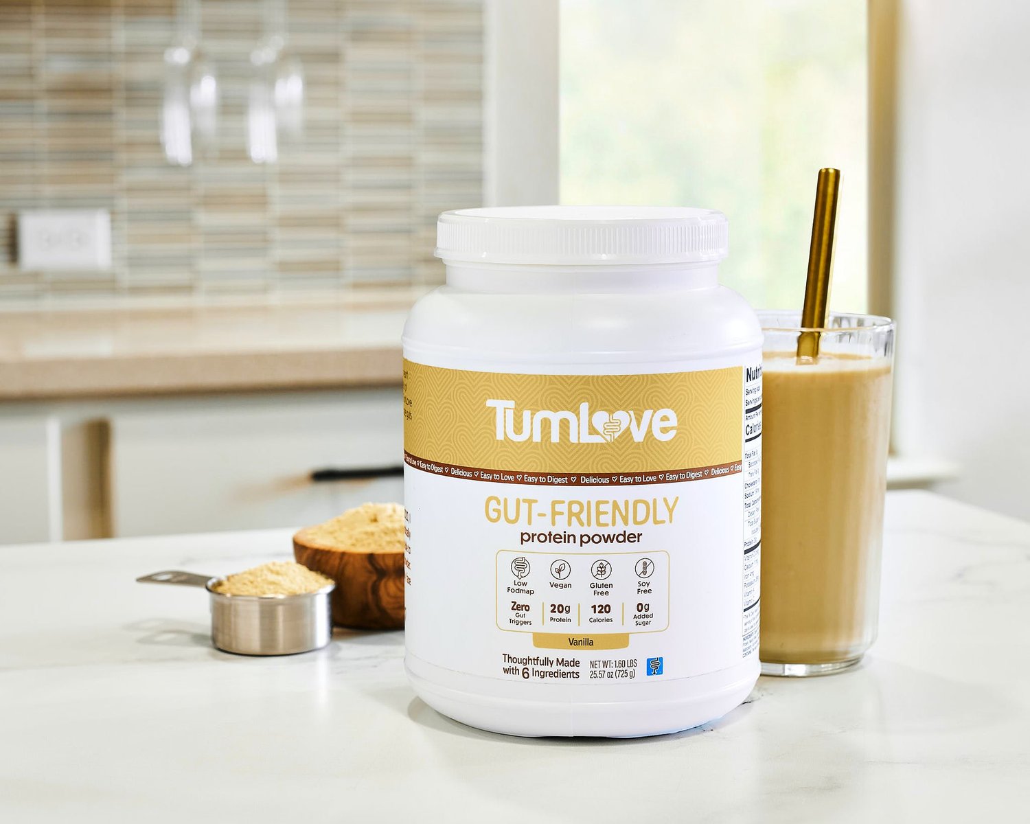 TUMLOVE gut-friendly protein powder container beside a protein shake on a kitchen counter
