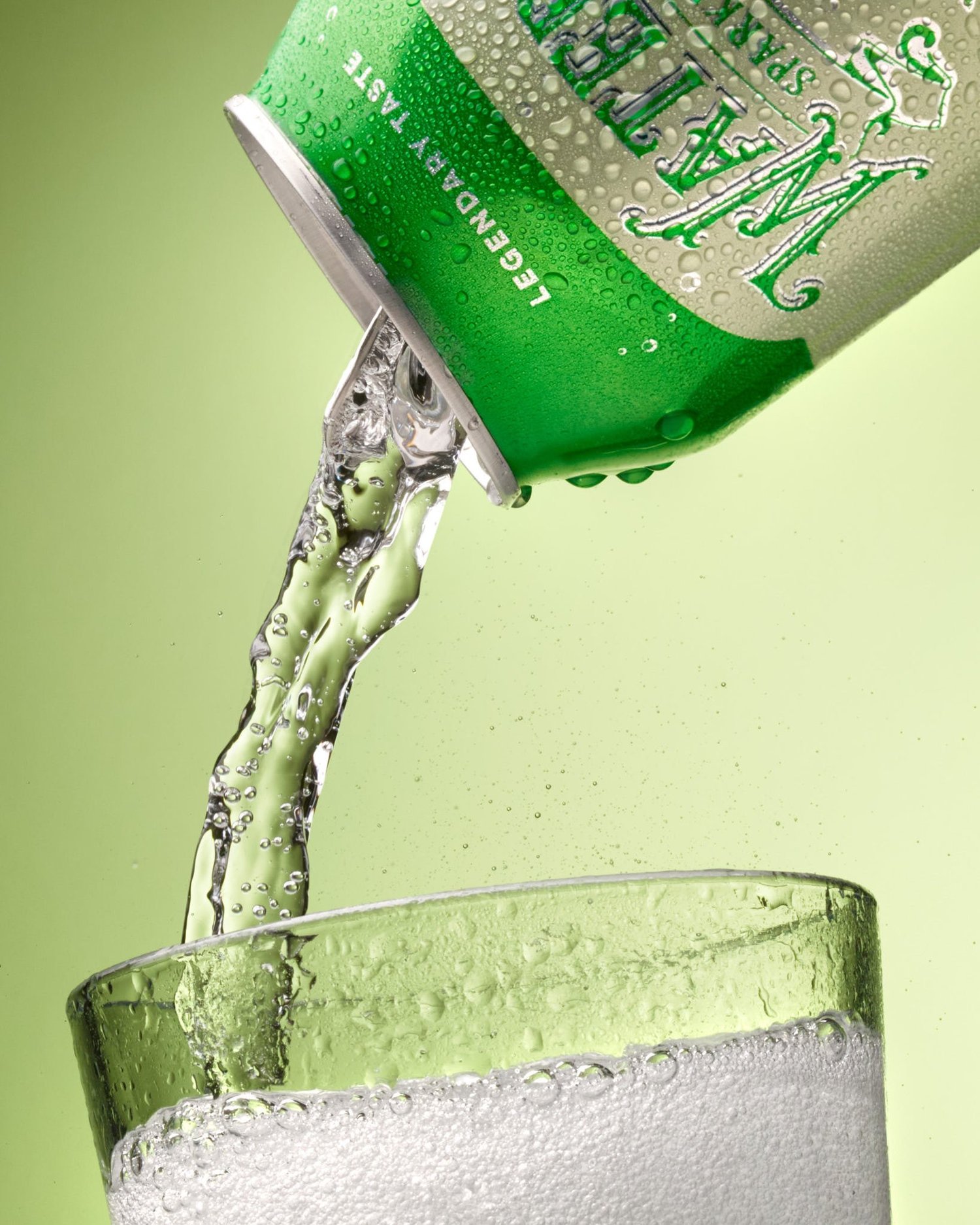 Styled product photography of a Waterloo sparkling water can mid-pour