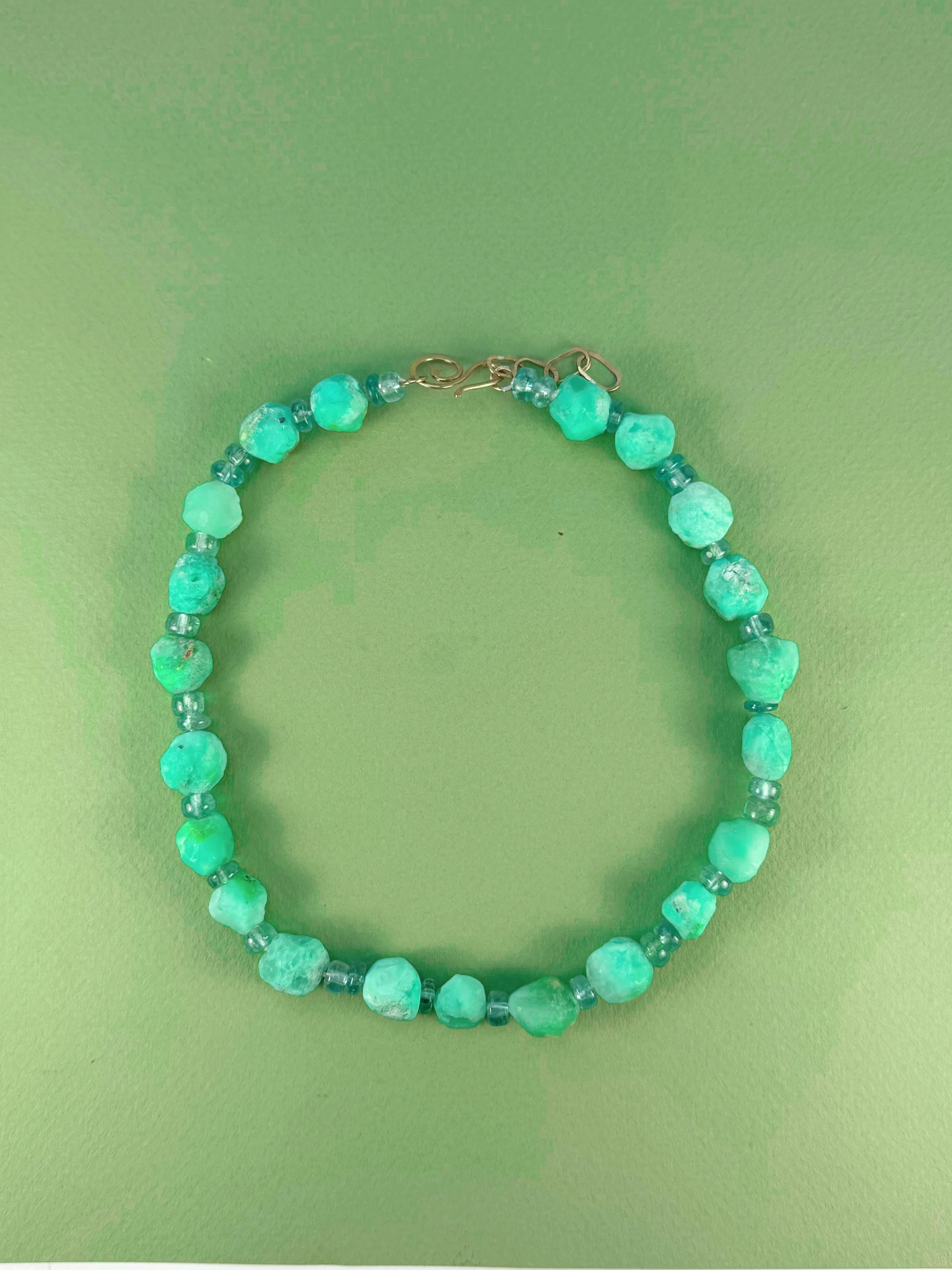 calcite and apatite stone bead necklace on green background