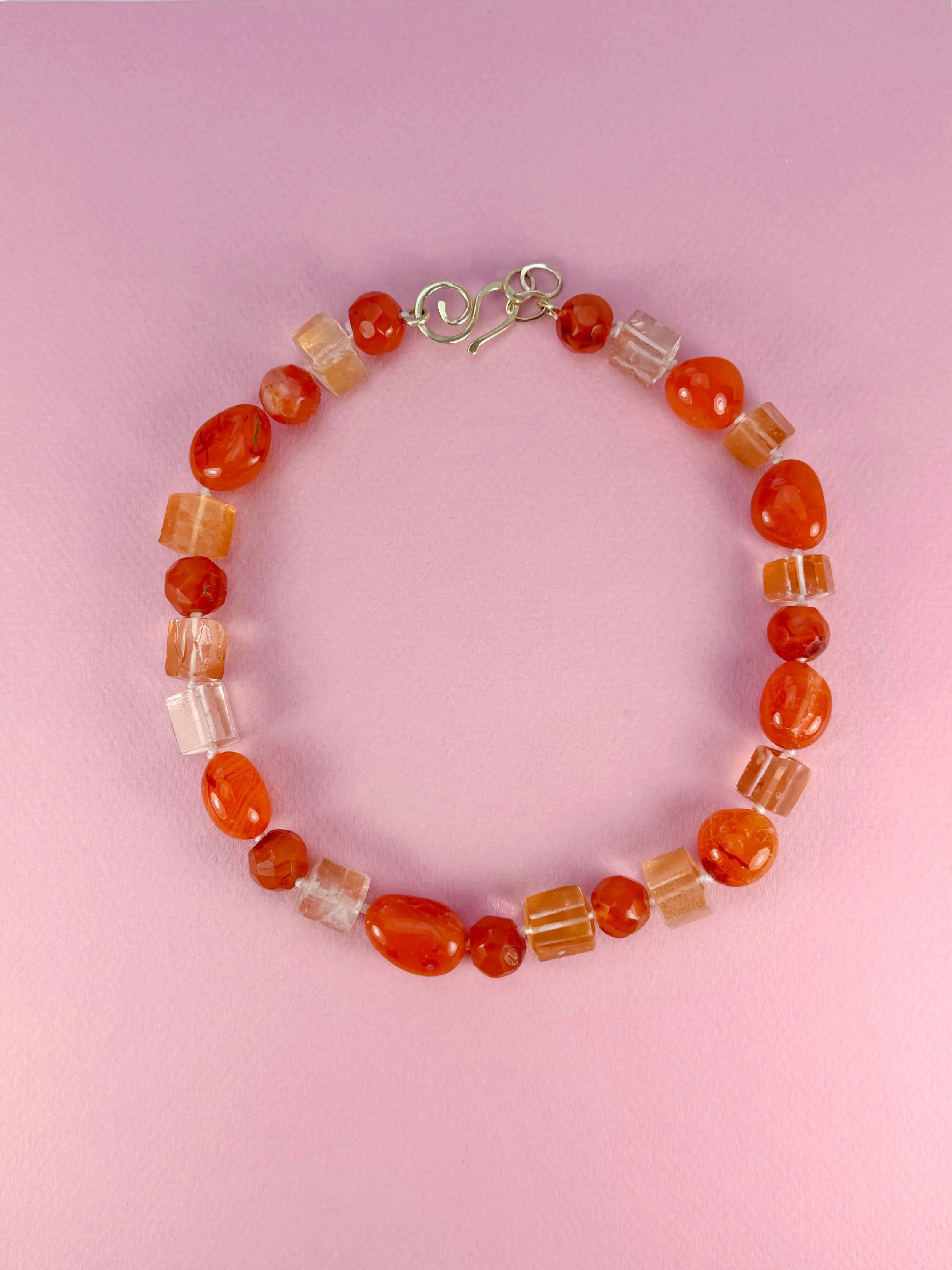 carnelian and red quartz stone bead necklace on pink background
