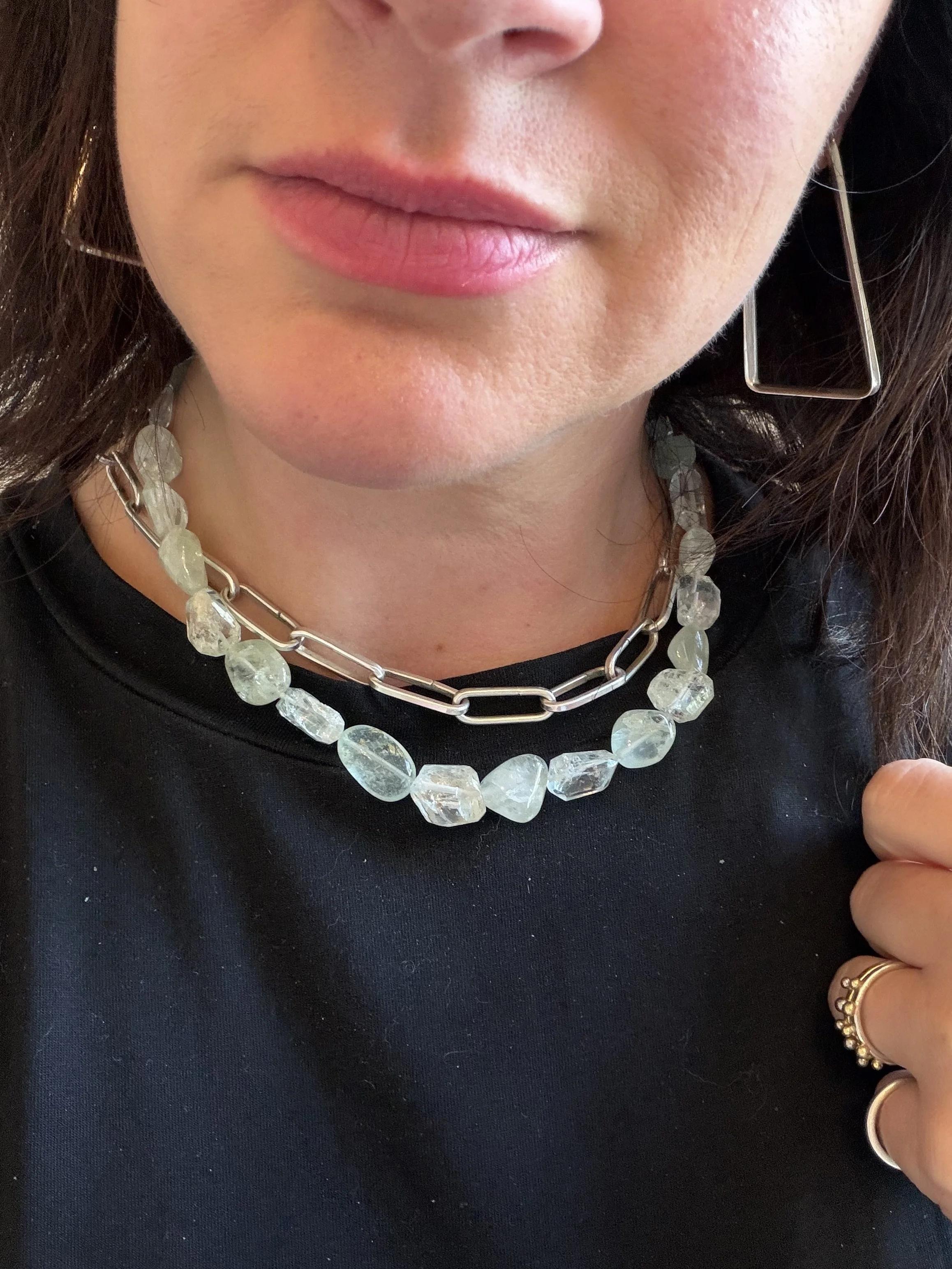 aquamarine stone bead necklace worn on woman layered with silver chain