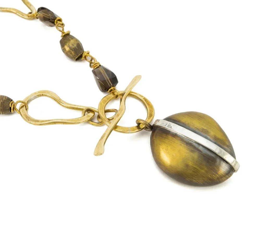 Hand-shaped organic bronze links and beads. Faceted smoky quartz. Sterling silver accents. A bold hollow-form pendant anchored by an oversized toggle&mdash;crafted with contrast, texture, and intention. Modern statement art for those who value indivi