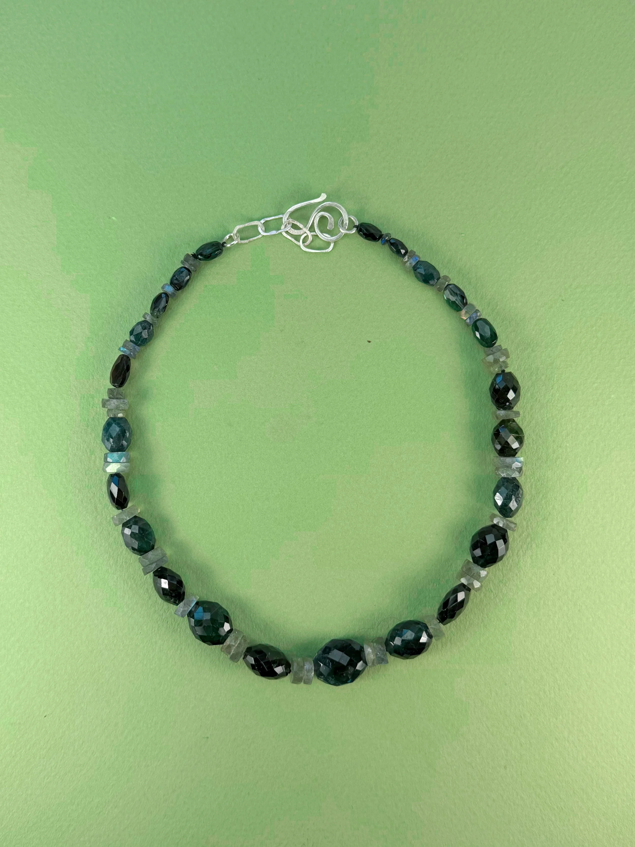 green tourmaline and labradorite stone bead necklace on green background