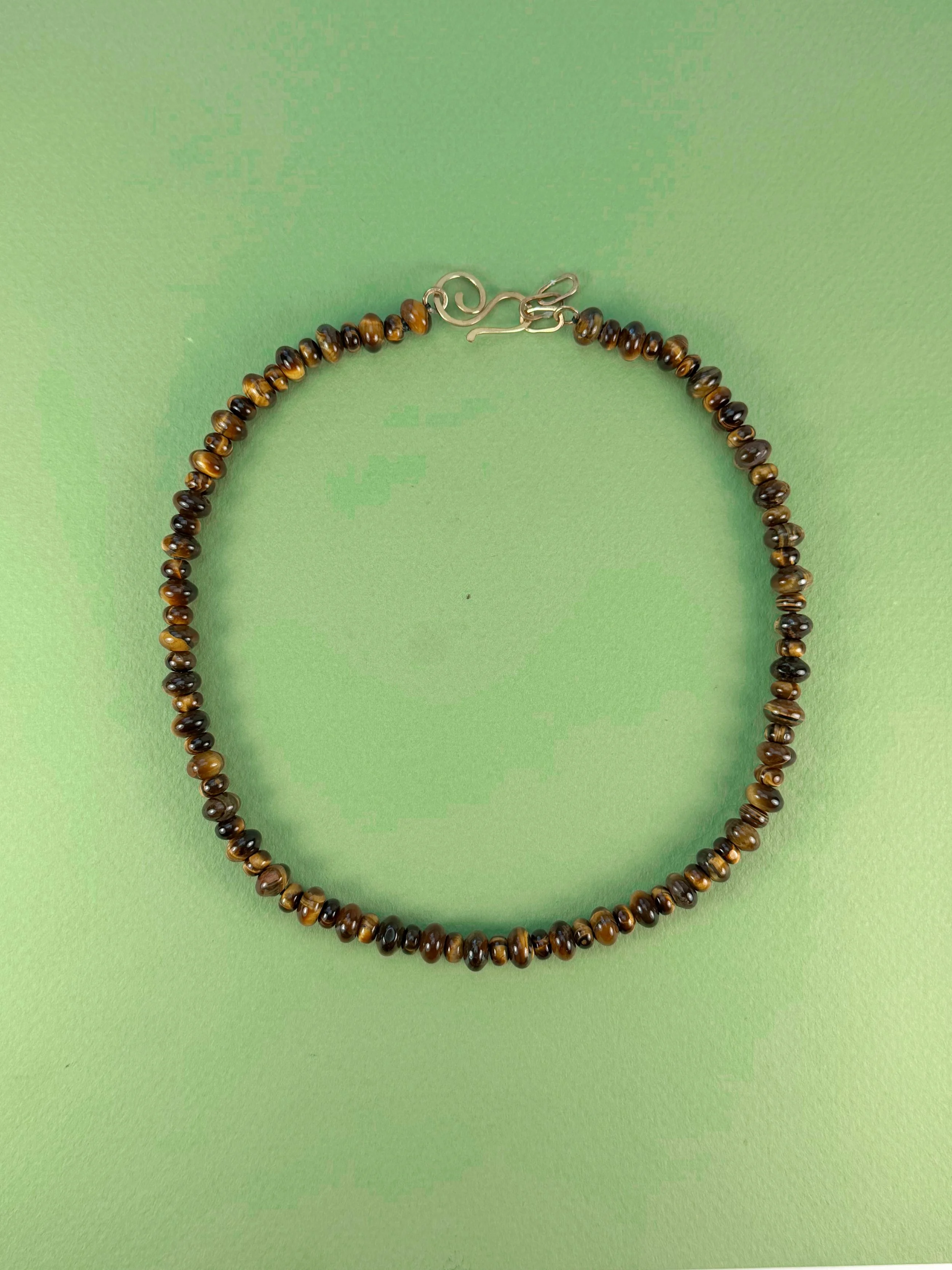 Tiger Eye Stone Bead Necklace on green background