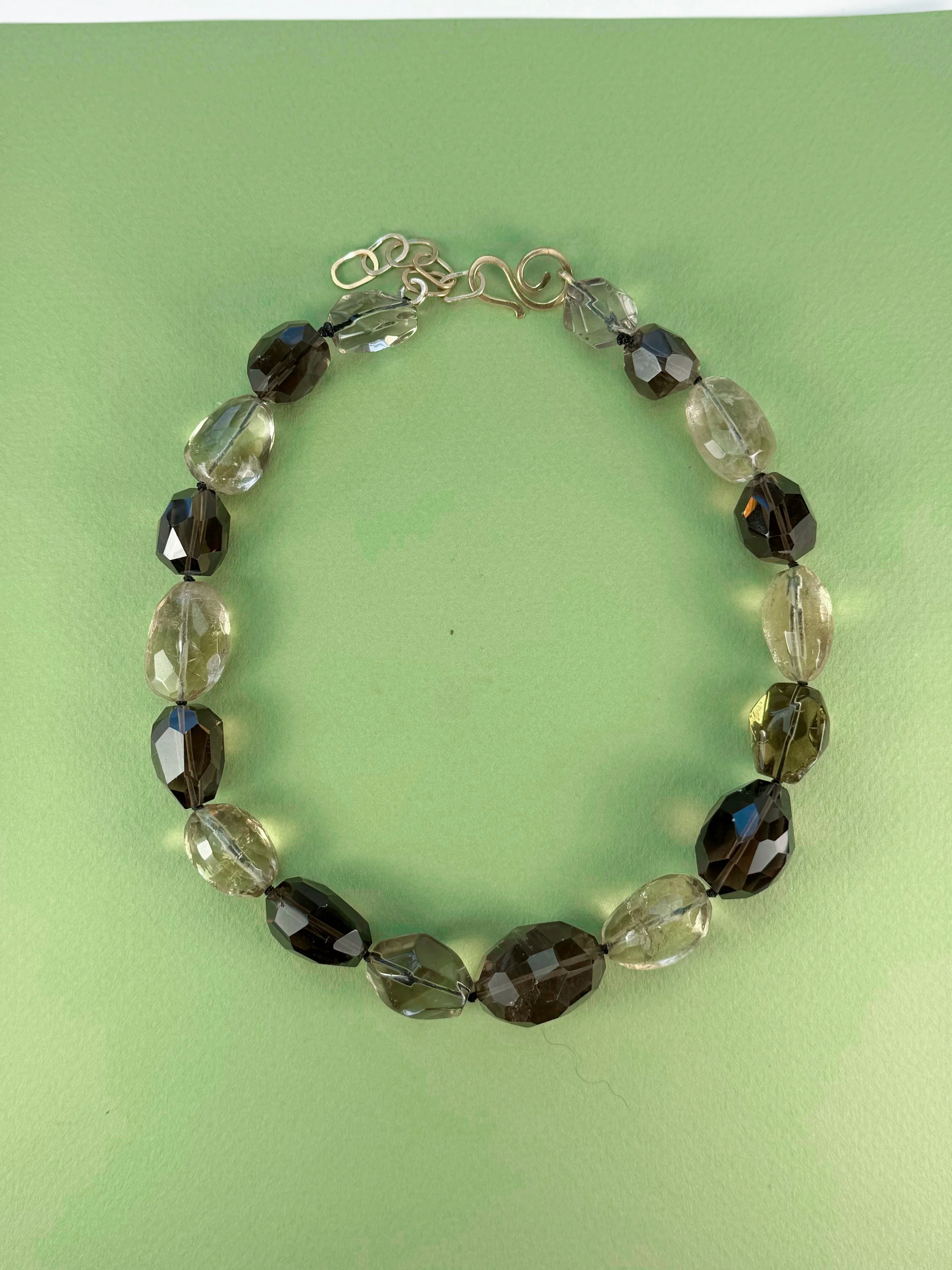 citrine and smoky quartz stone bead necklace on green background