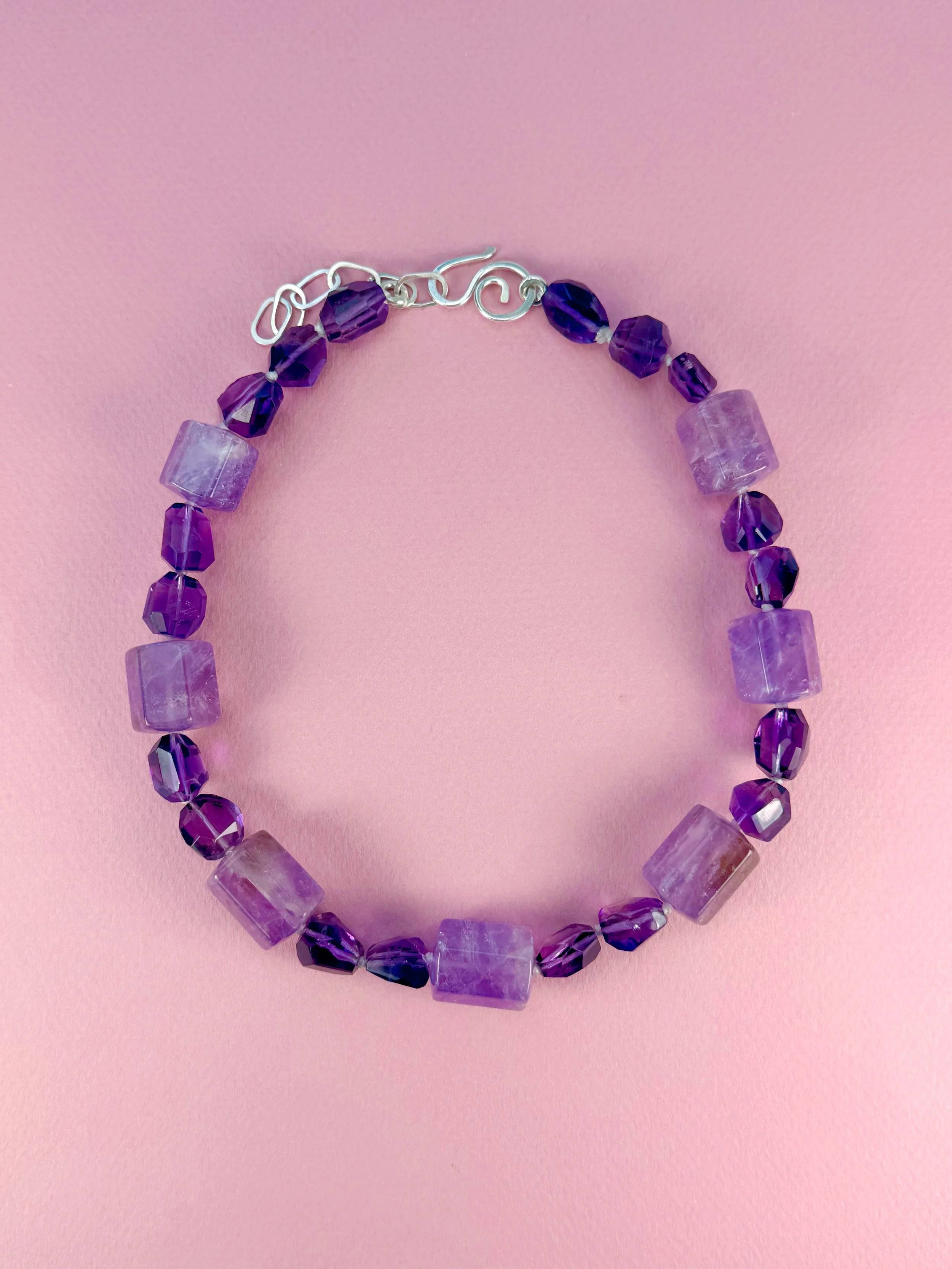amethyst stone bead necklace on pink background