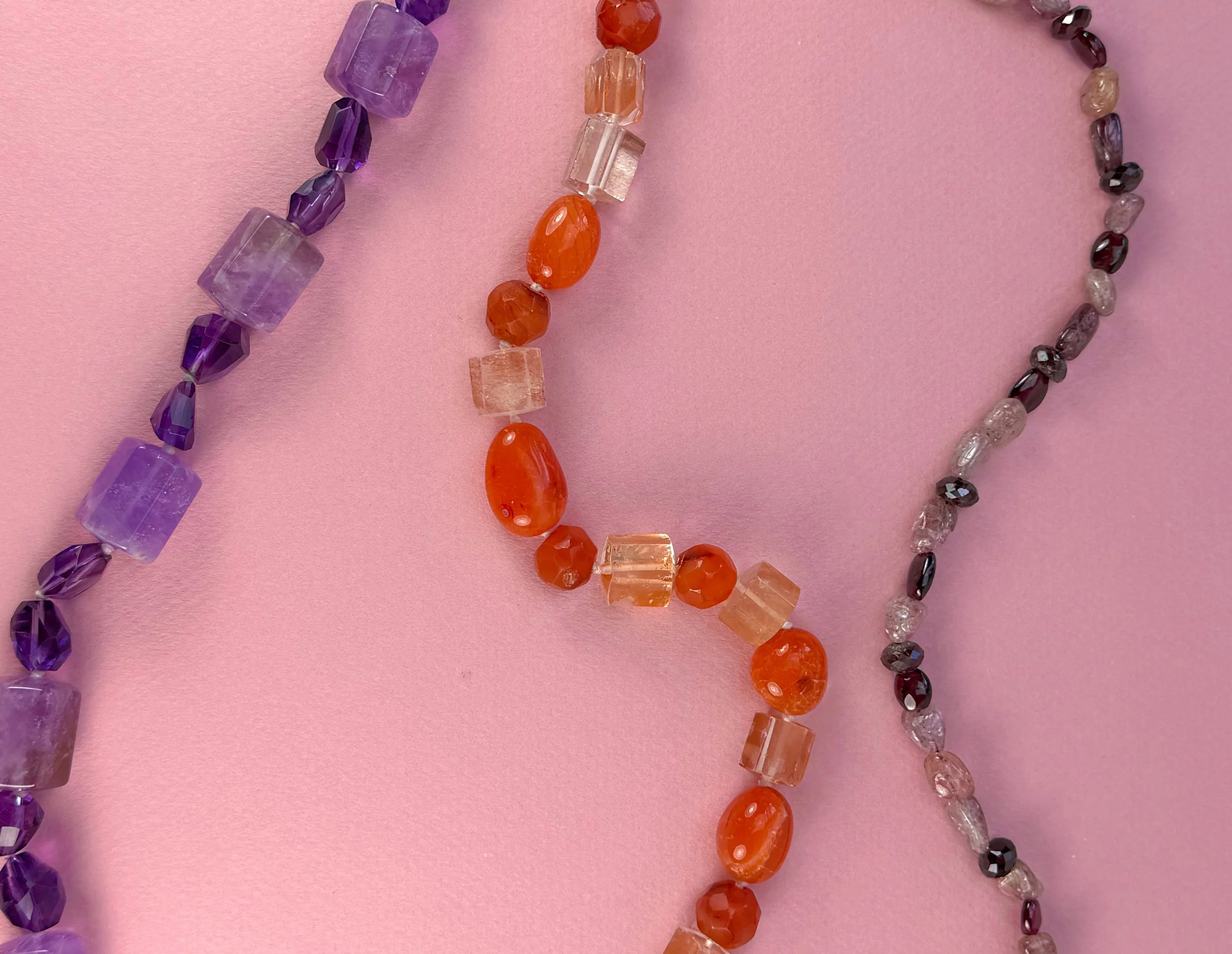 three semiprecious stone bead necklaces on pink background