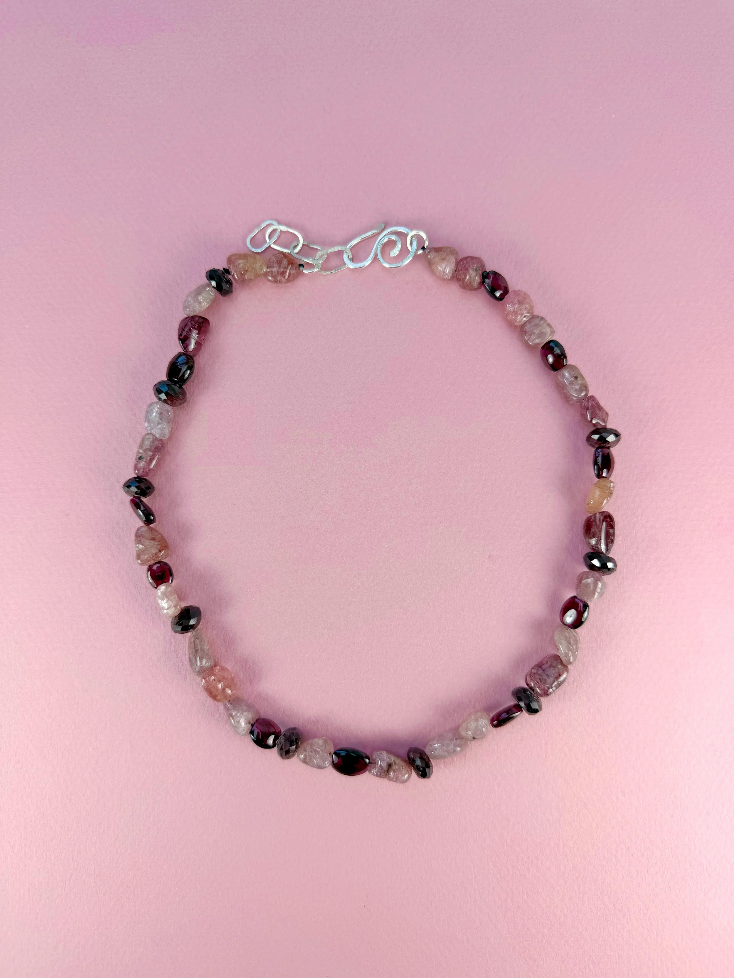 pink spinel and rhodolite garnet stone bead necklace on pink background