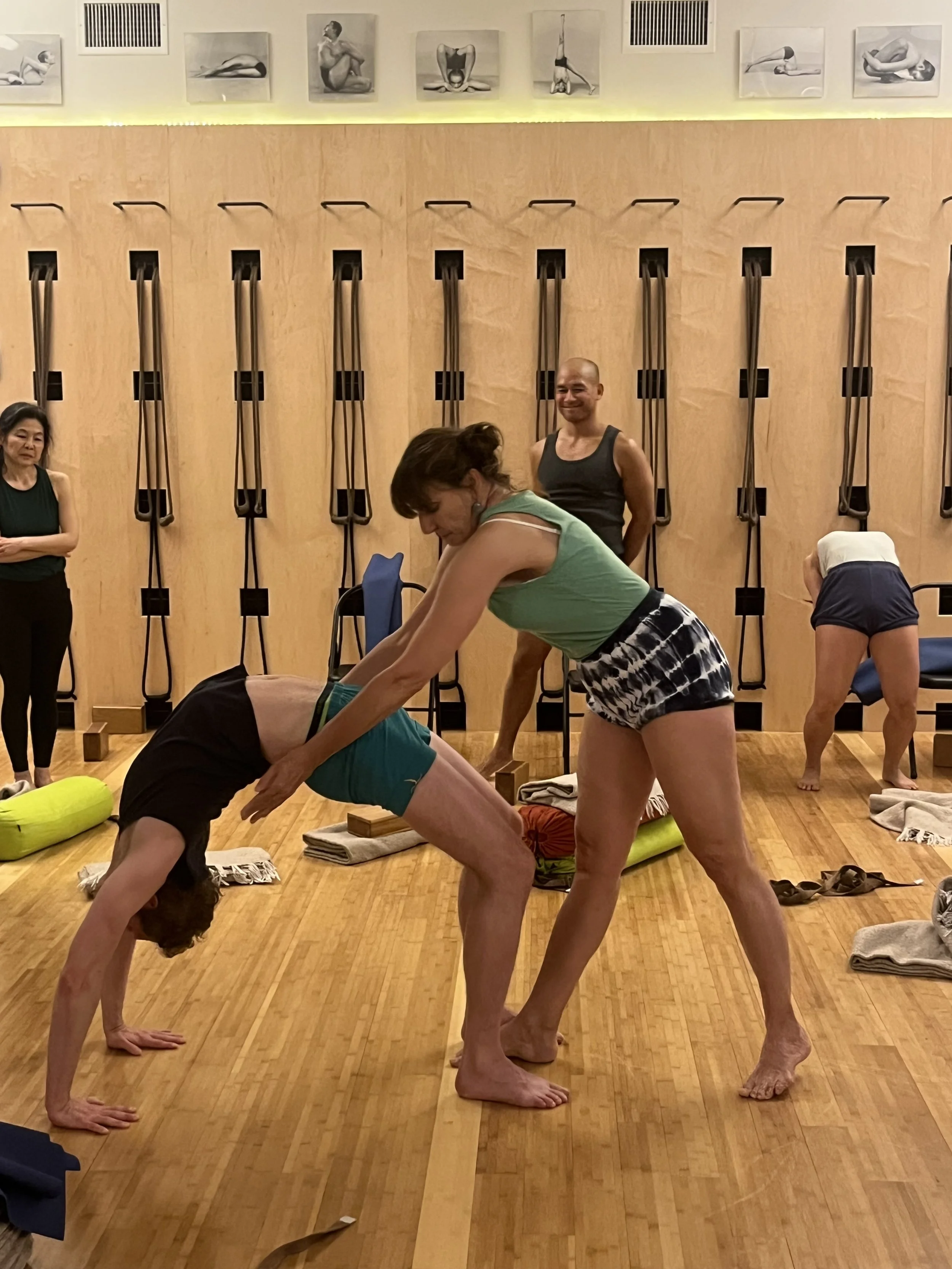 Senior Iyengar Yoga Teacher Lara Warren adjusting a student in wheel pose at the Iyengar Yoga Institute of New York, Chelsea.