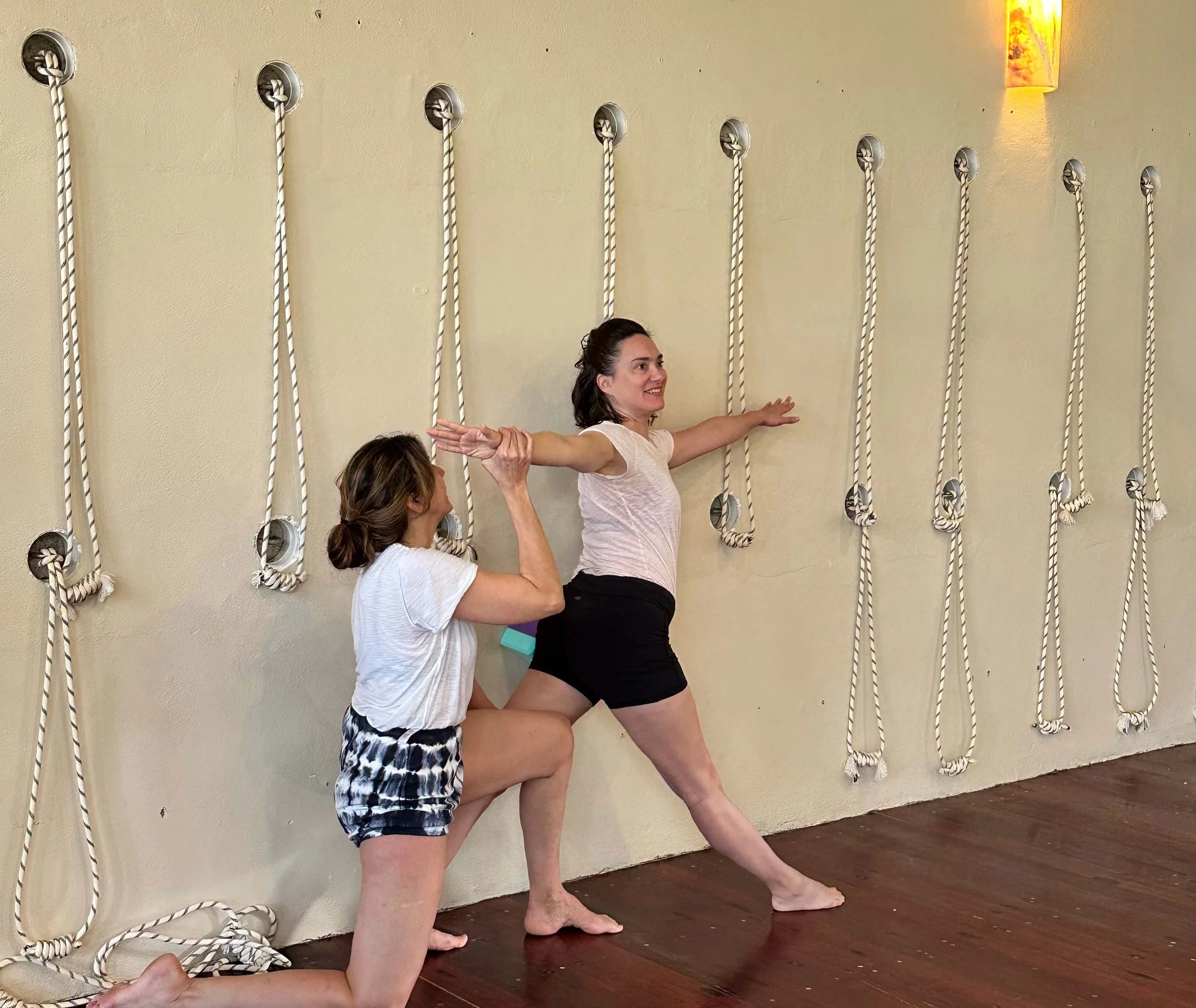 Seniro Iyengar Yoga Teacher adjusting a student in revolved triangle pose.