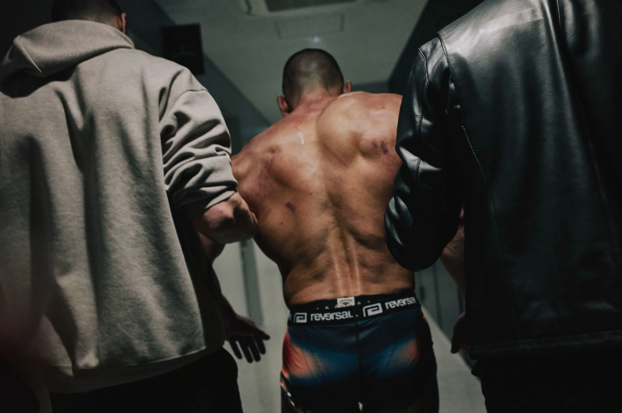 Fighter led through a corridor by his team before a bout — Shura No Hana MMA documentary, Tokyo | Victor Marvillet photographer