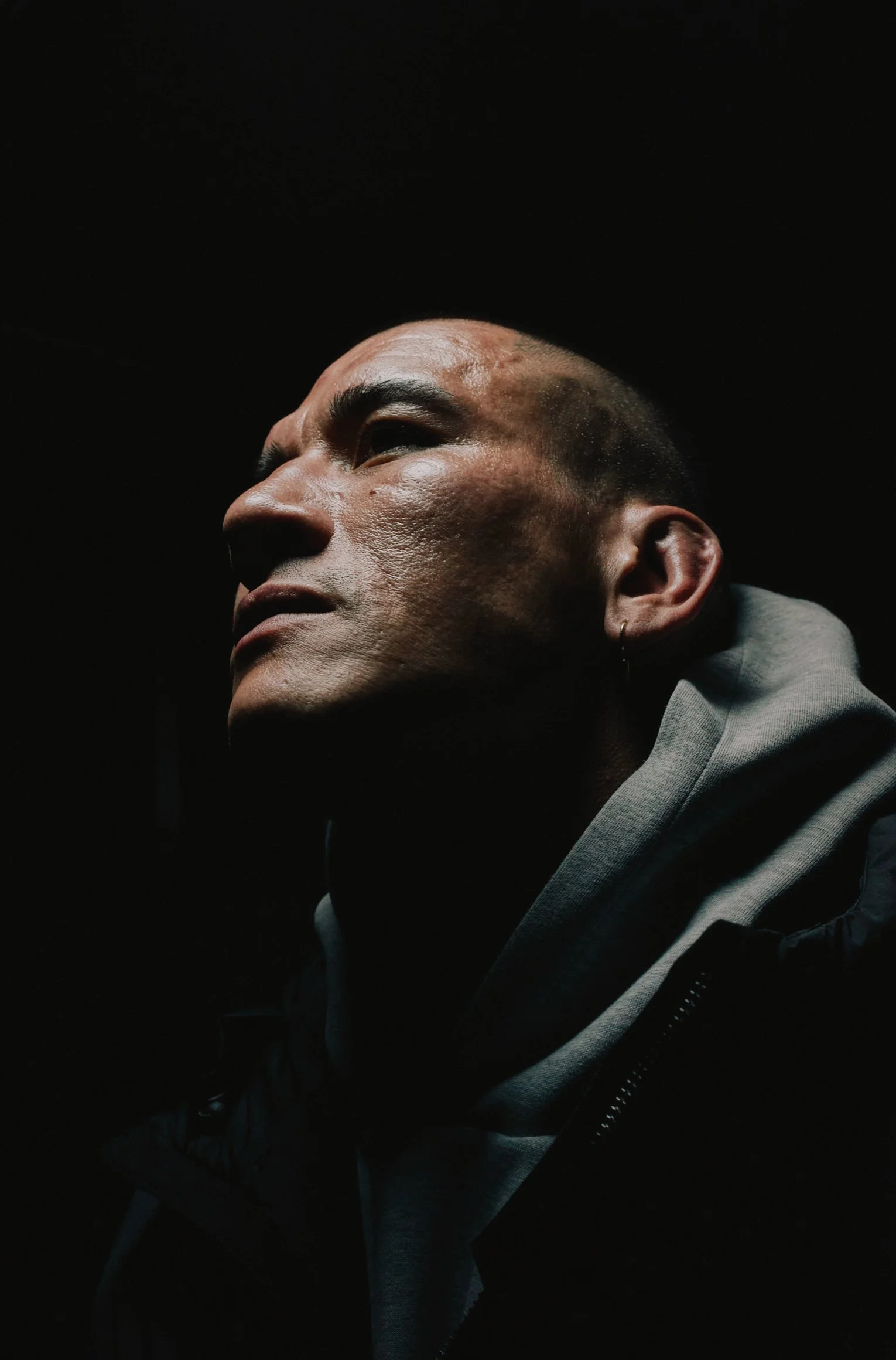 Portrait of a fighter in a hoodie in dramatic low light — Shura No Hana MMA documentary, Tokyo | Victor Marvillet photographer