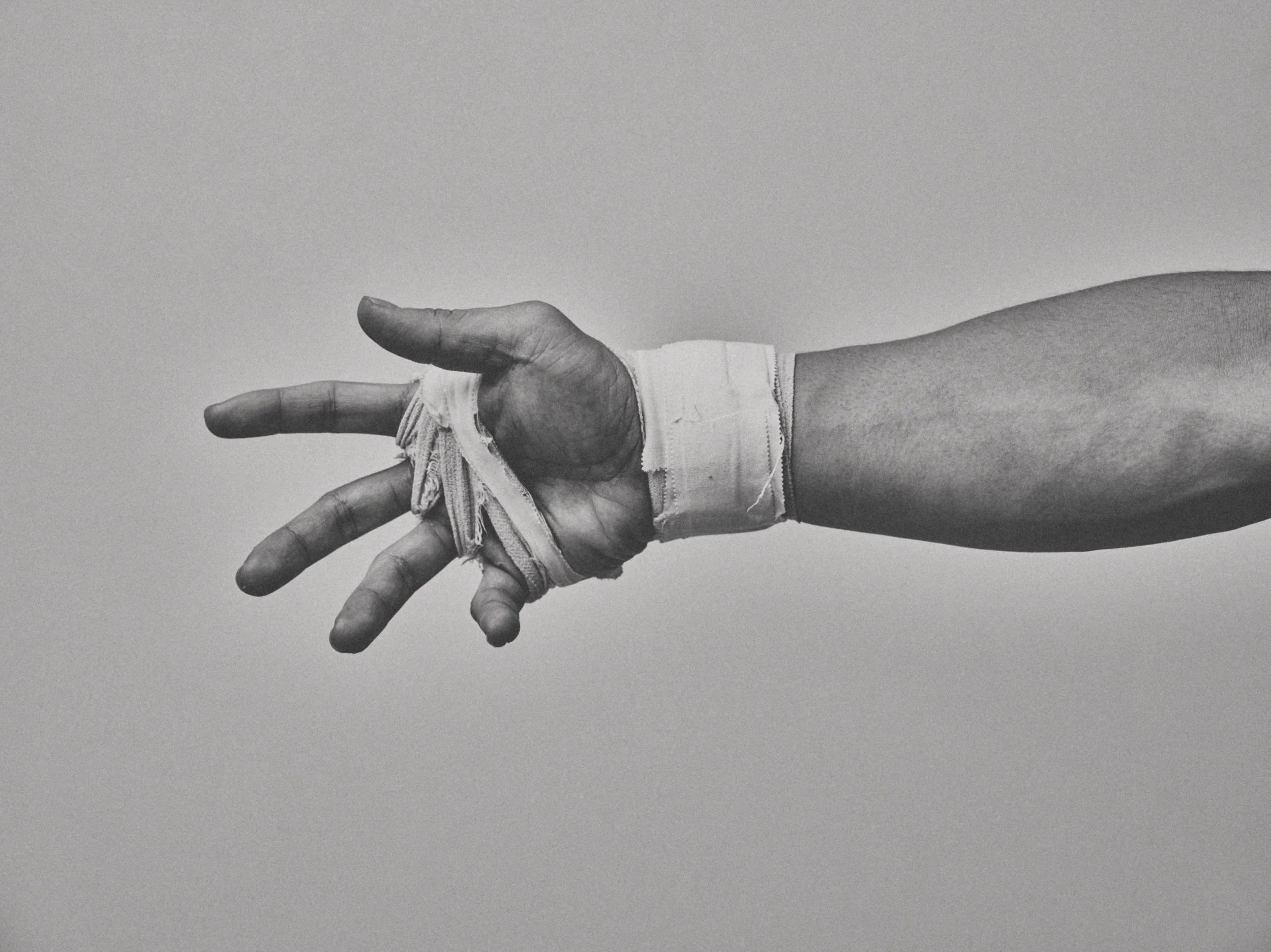 Black-and-white fighter's taped hand reaching out — Shura No Hana MMA documentary, Tokyo | Victor Marvillet photographer