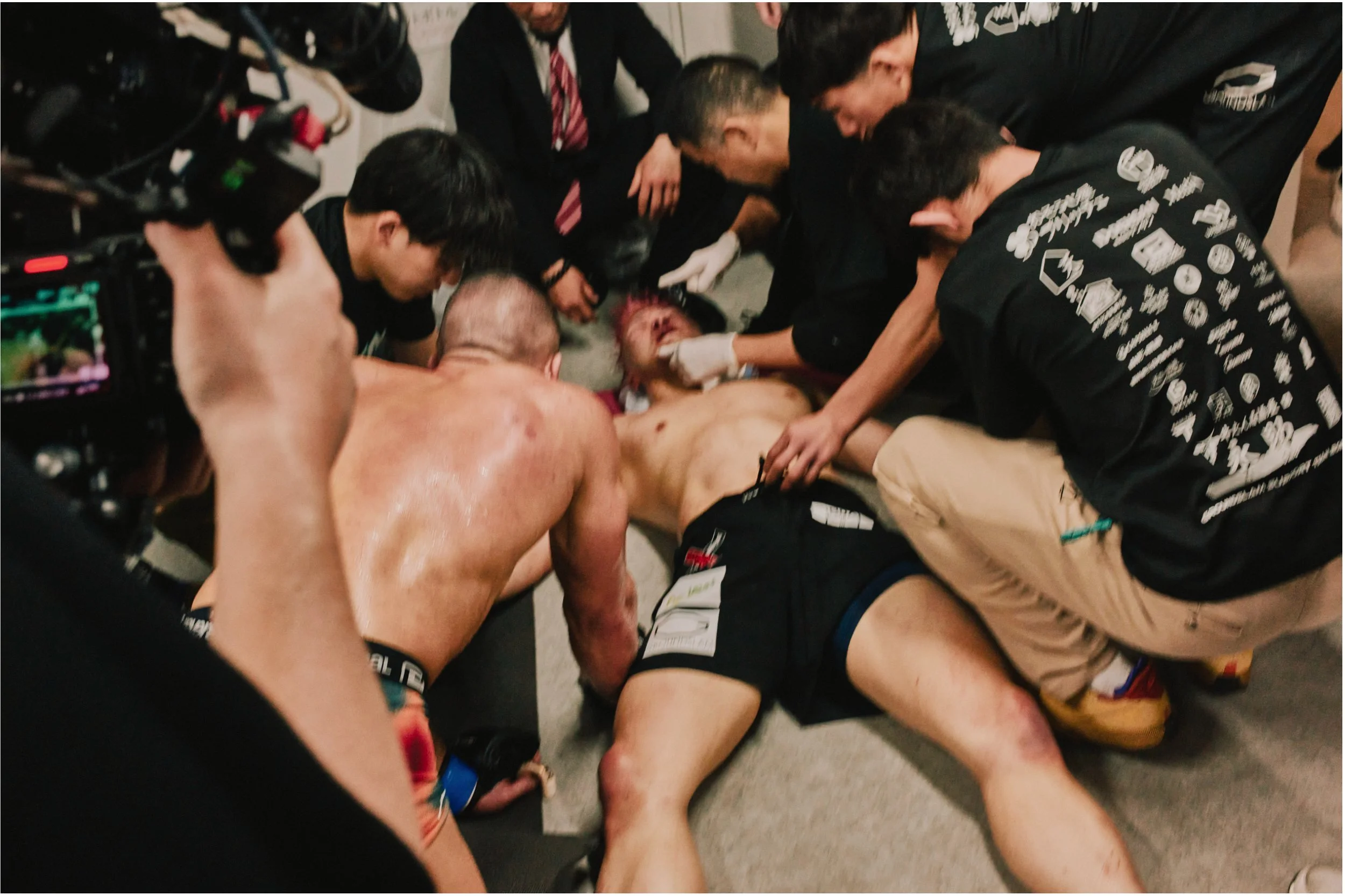 MMA fighter collapsed in the corner surrounded by his team — Shura No Hana MMA documentary, Tokyo | Victor Marvillet photographer