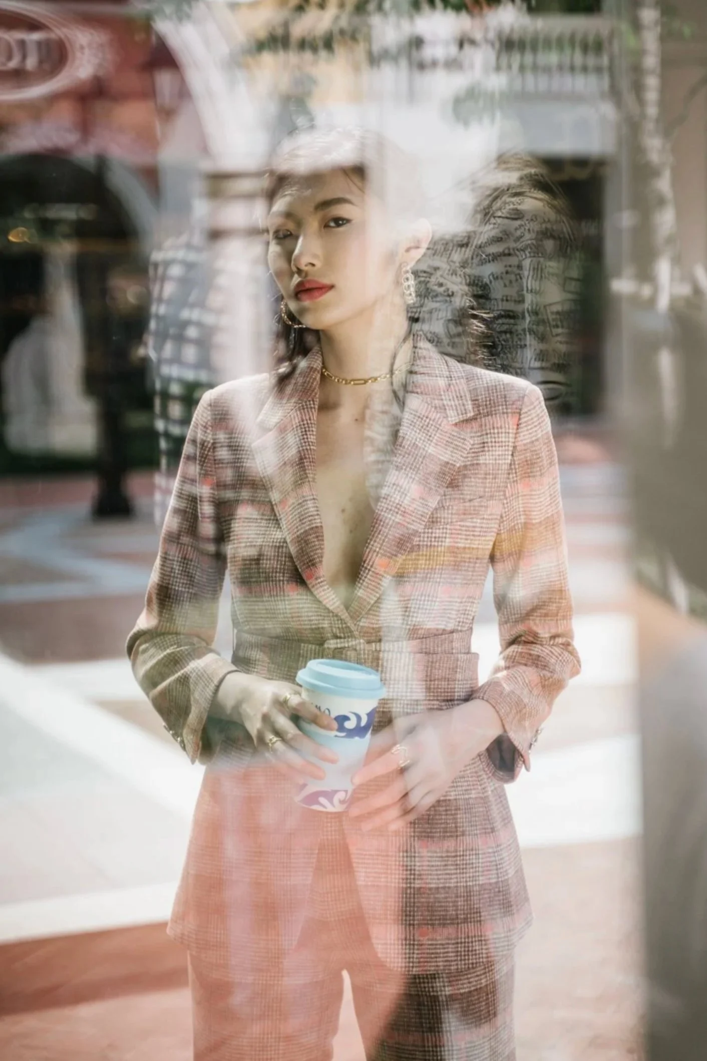 Woman in a plaid blazer seen through a reflective shop window — Shanghai fashion and portrait photography | Victor Marvillet photographer