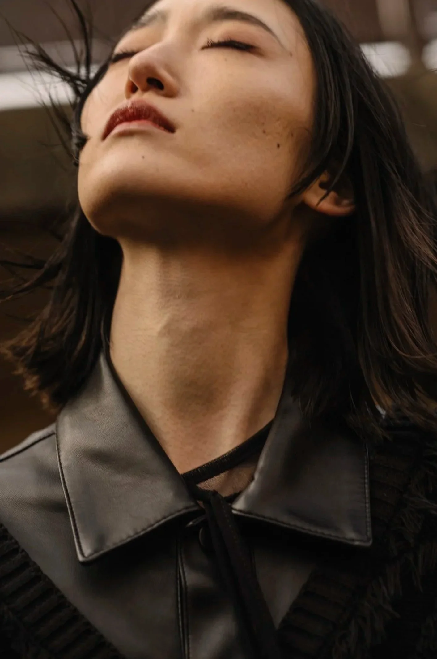 Woman with eyes closed in black leather jacket against blurred city lights, Tokyo cityscape series, Tokyo — Victor Marvillet photographer