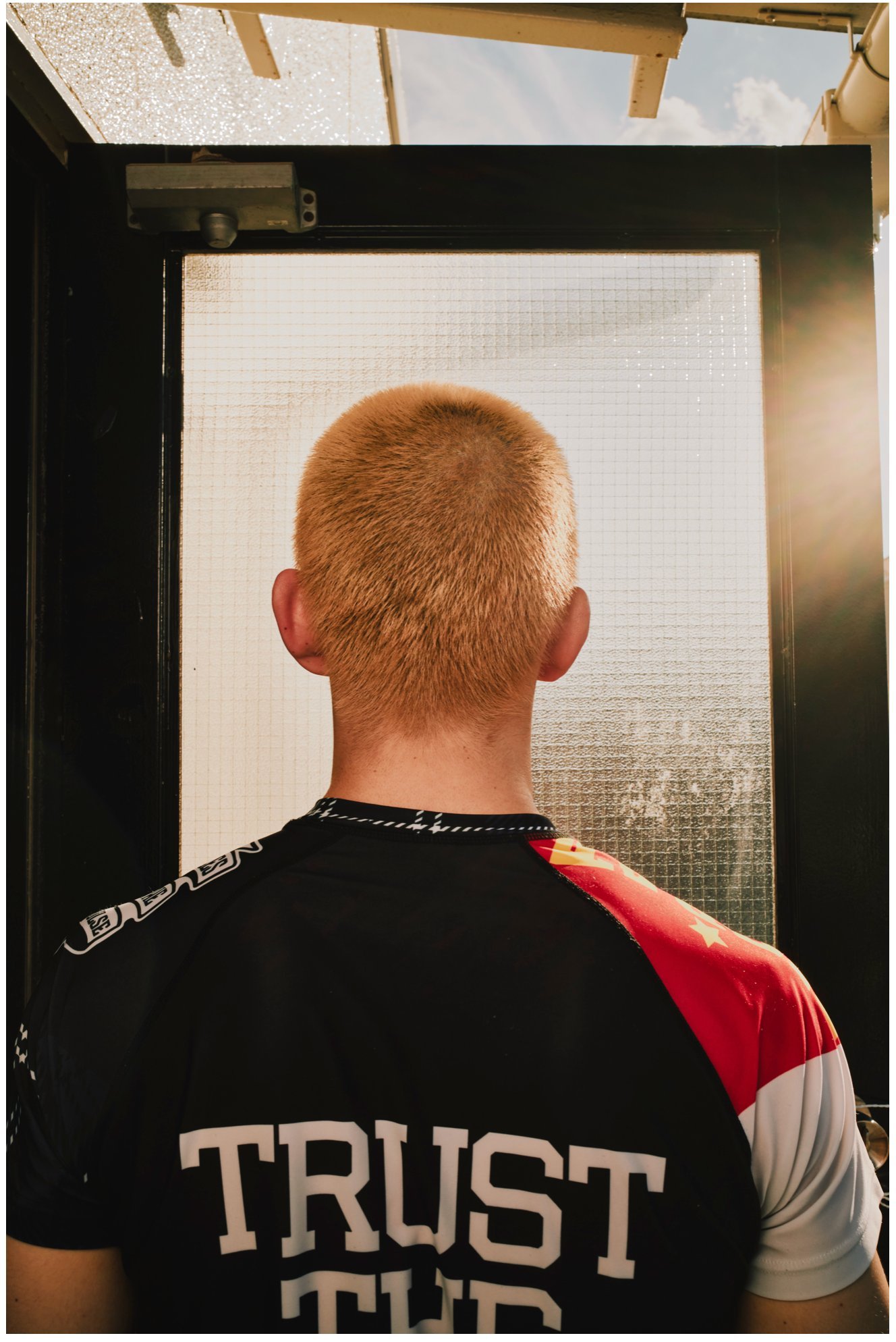 Back of a fighter's shaved head in a team shirt — Shura No Hana MMA documentary, Tokyo | Victor Marvillet photographer